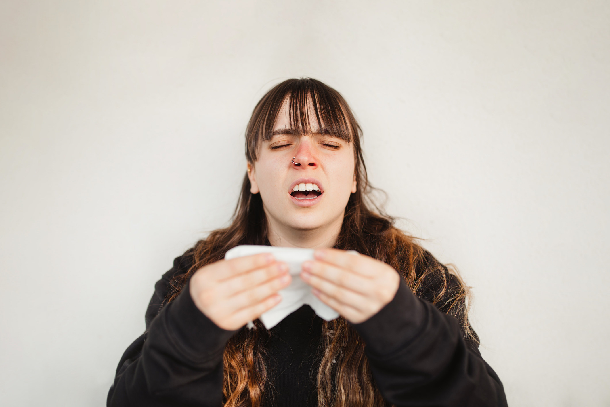 A person about to sneeze and holding tissue