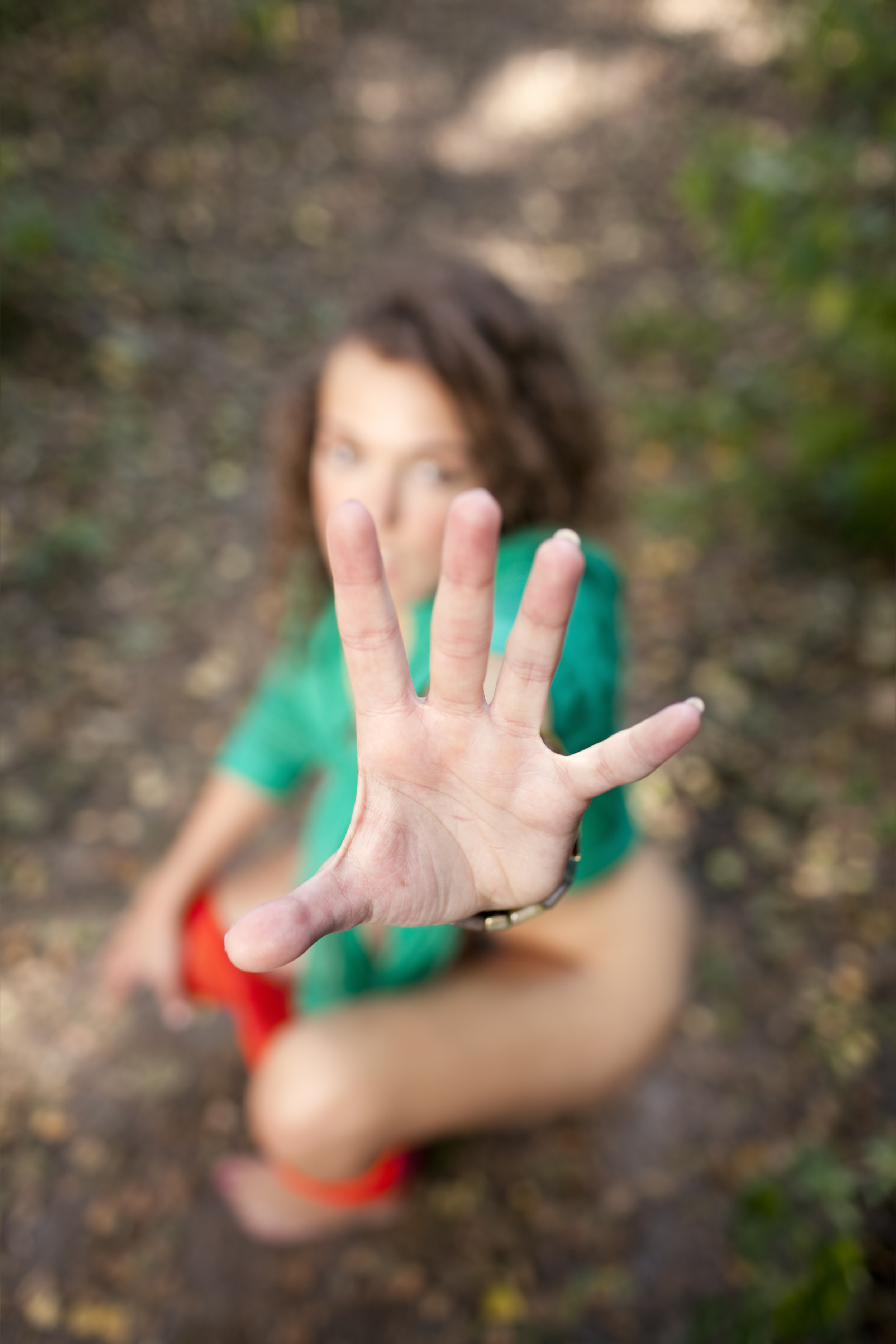 A woman peeing in the woods and holding out her hand
