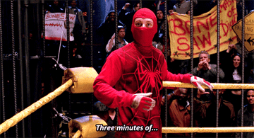 A confused spider-man stands in a caged wrestling ring