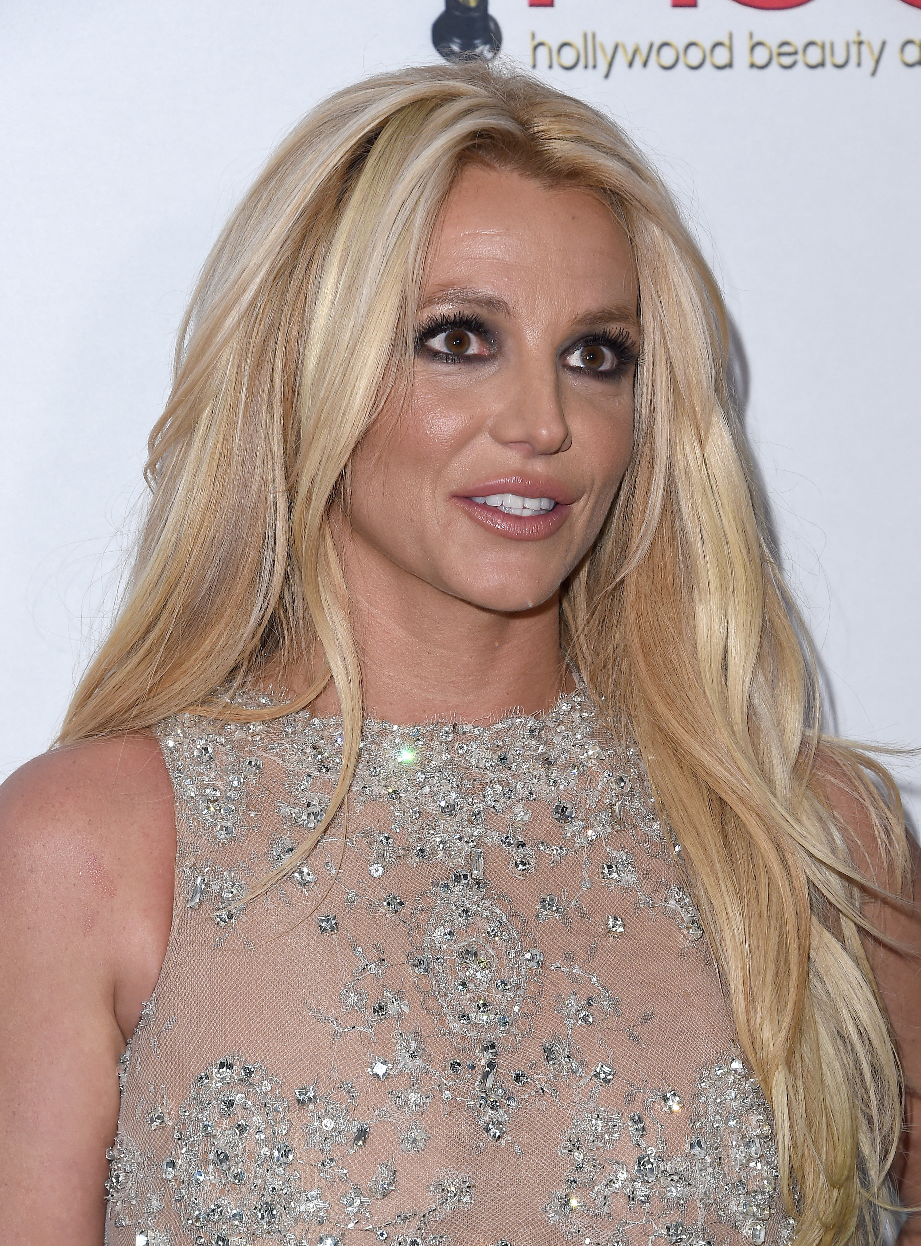 A close-up of Britney in a sleeveless shiny, diaphanous outfit
