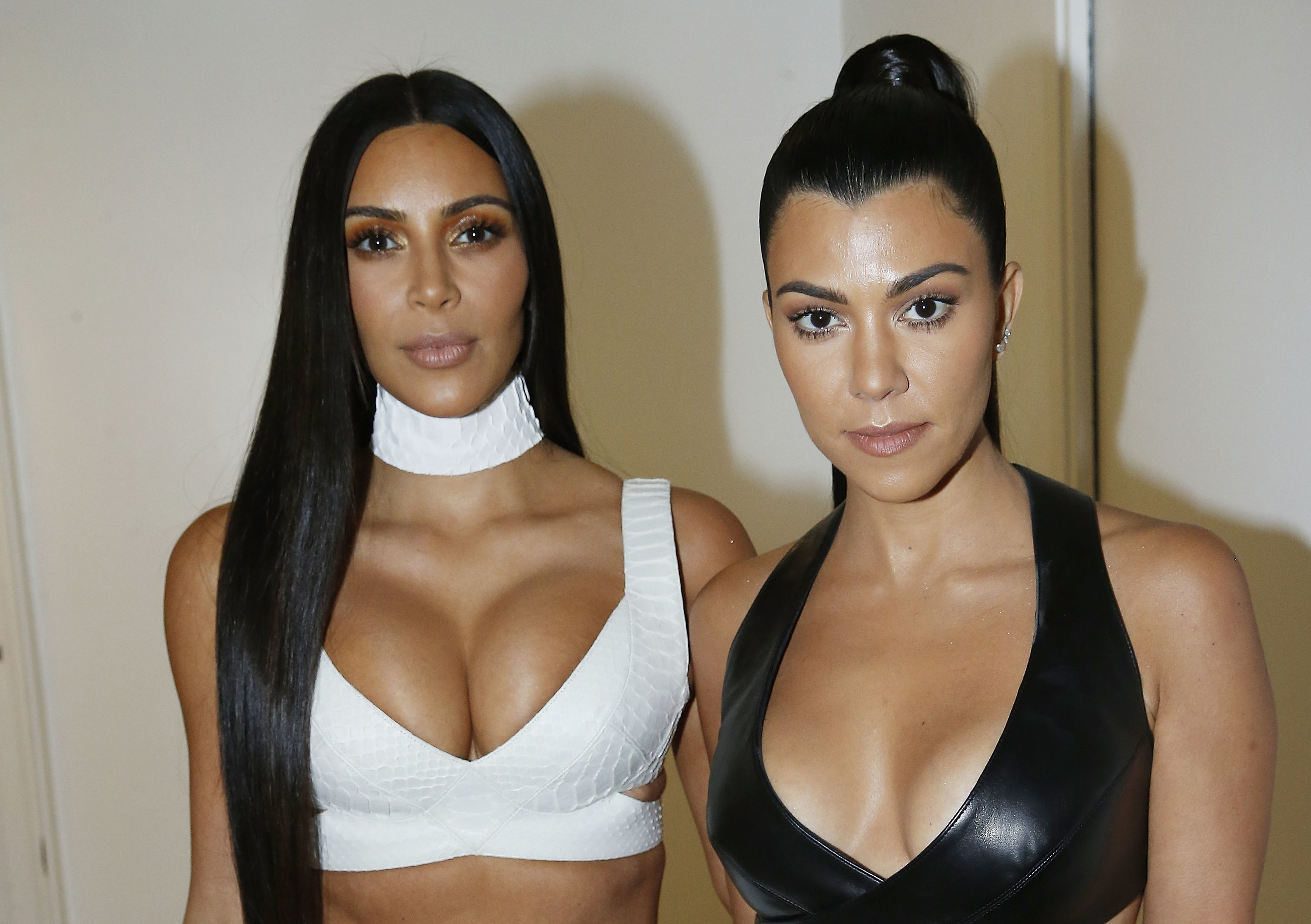 Kim and Kourtney standing together and wearing bra-type tops