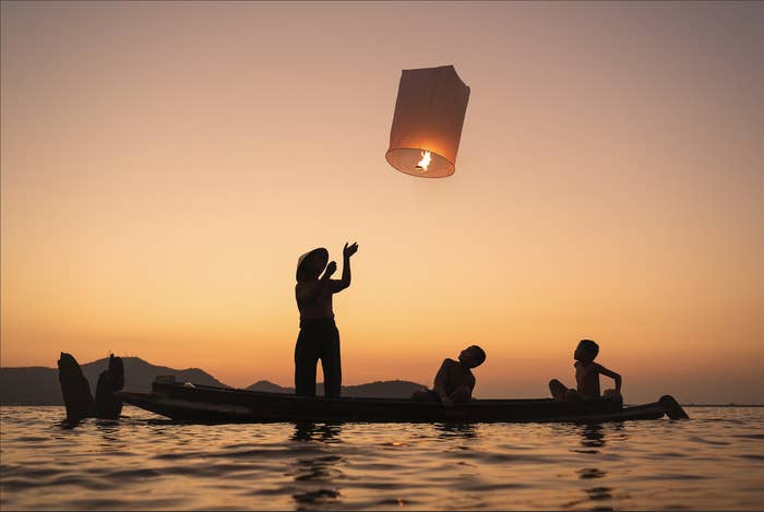 Fisher setting off lantern in ocean at sunset