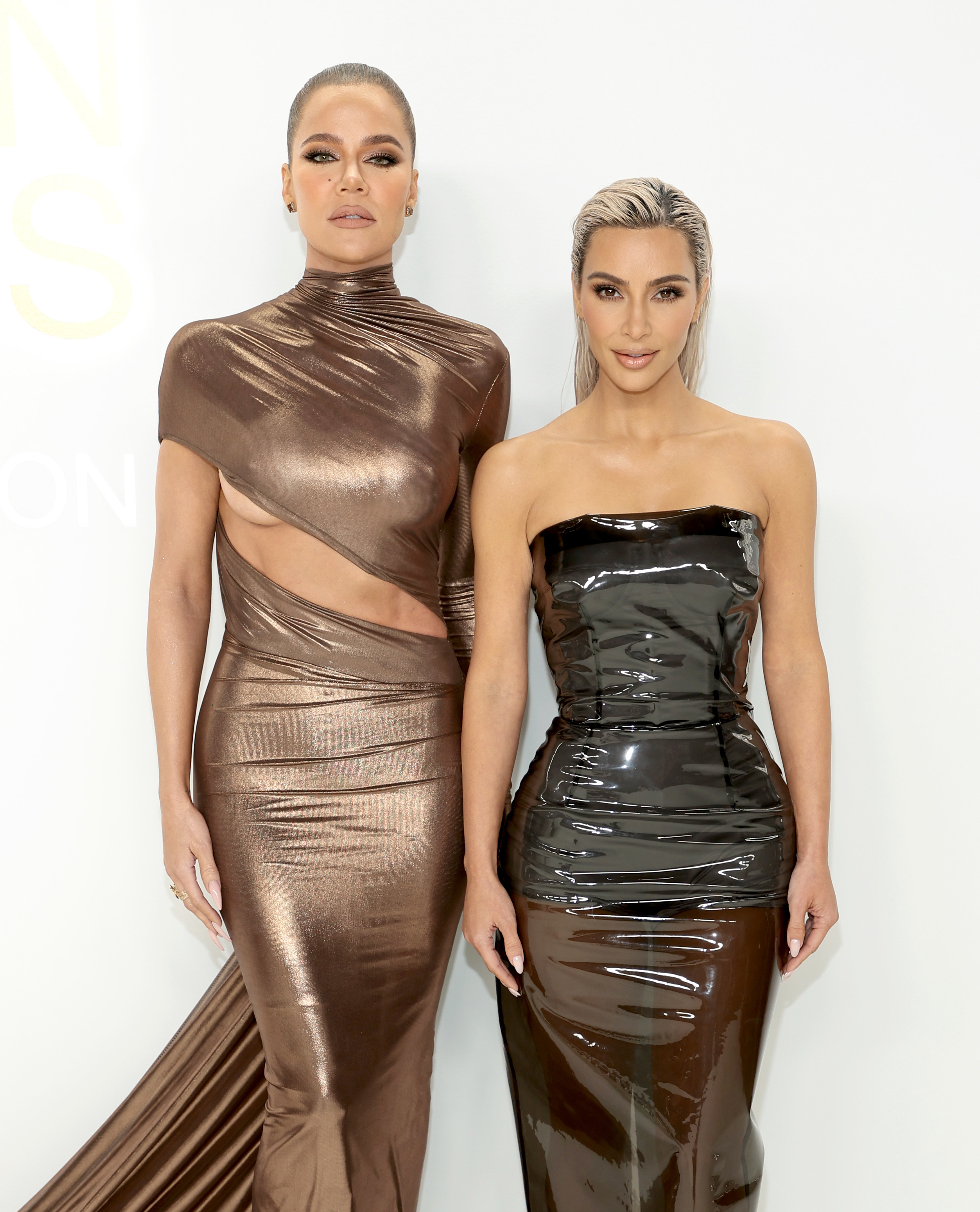 Khloé and Kim standing together in shiny gowns