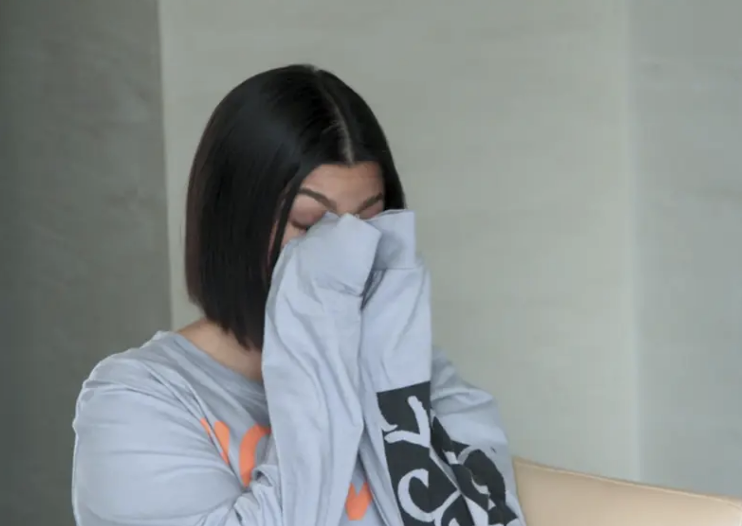 Kourtney covering her face with her hands