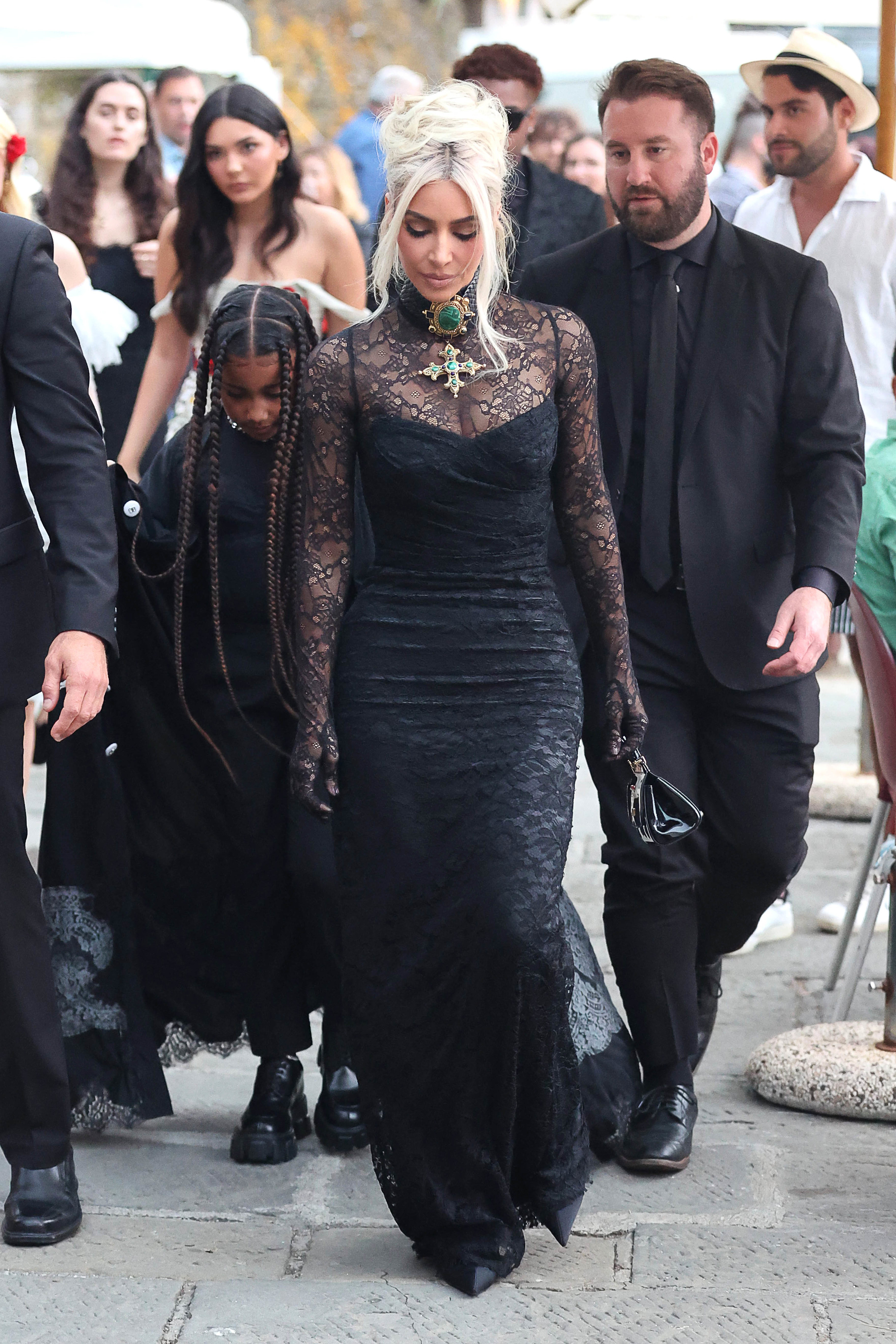 Kim on the street with a crowd and wearing a lacy gown