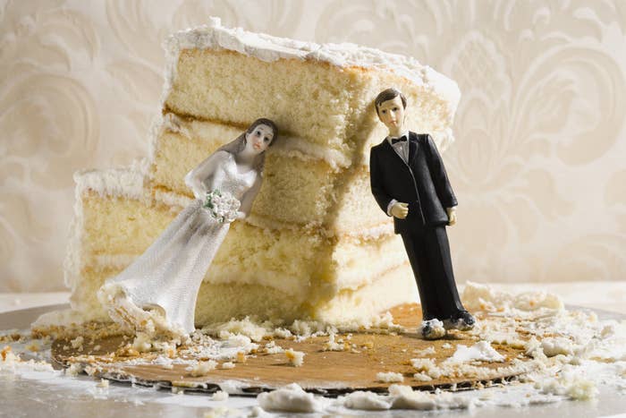 A dismantled wedding cake with cake toppers leaning on it