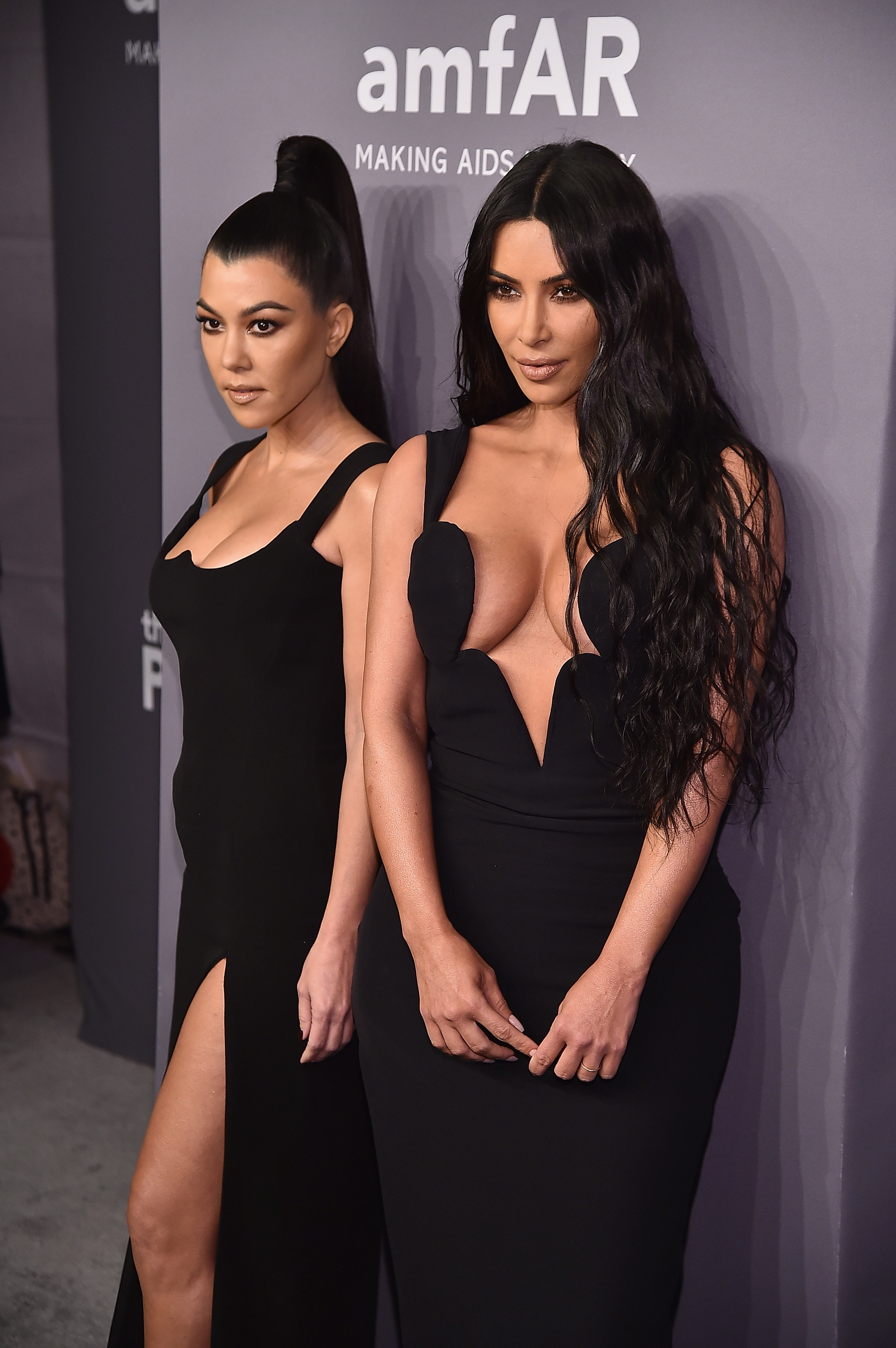 Kourtney and Kim standing together in gowns at a press event