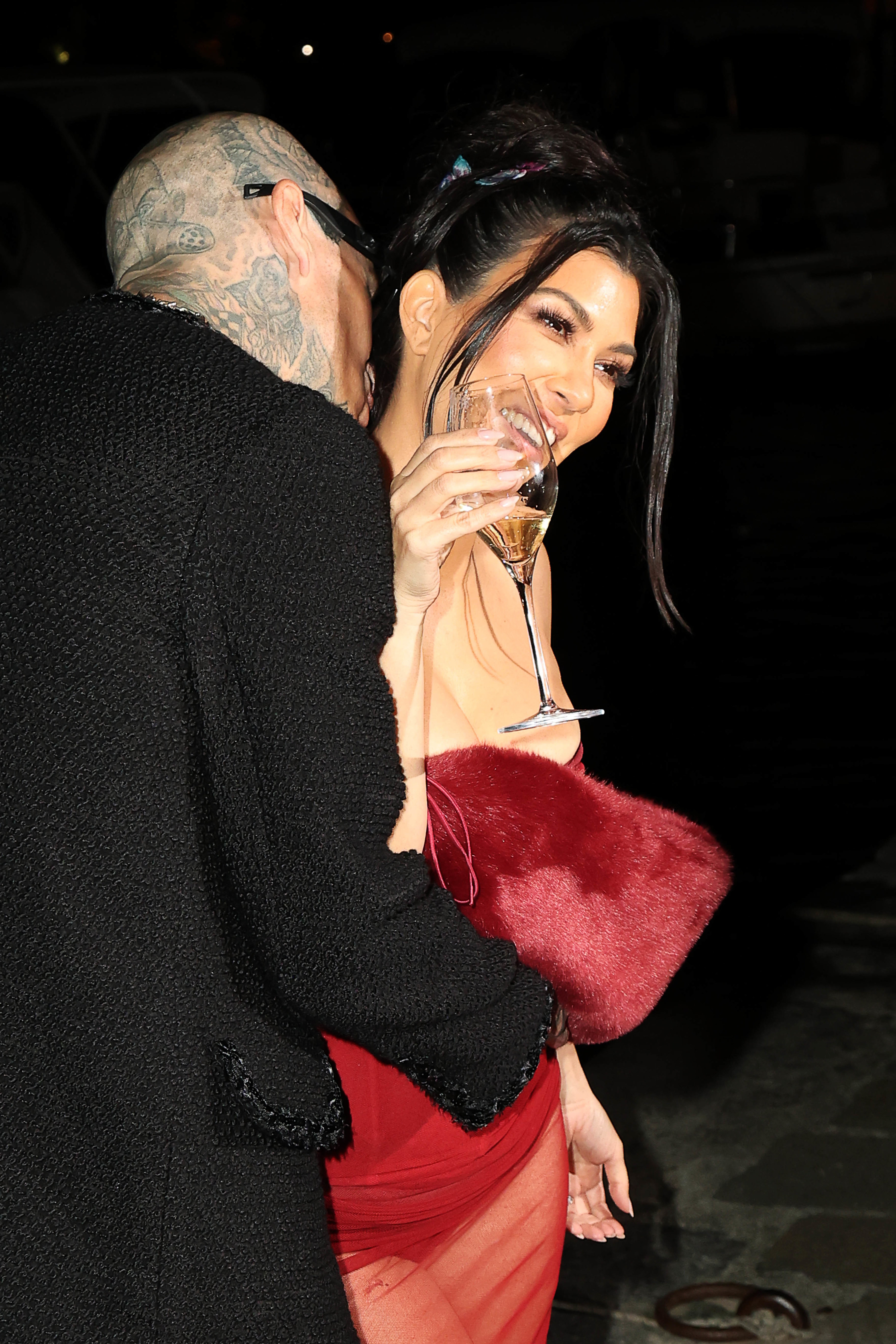 Kourtney with Travis Barker and holding a glass of champagne