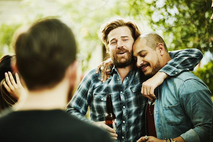 Two men drinking beer and hugging