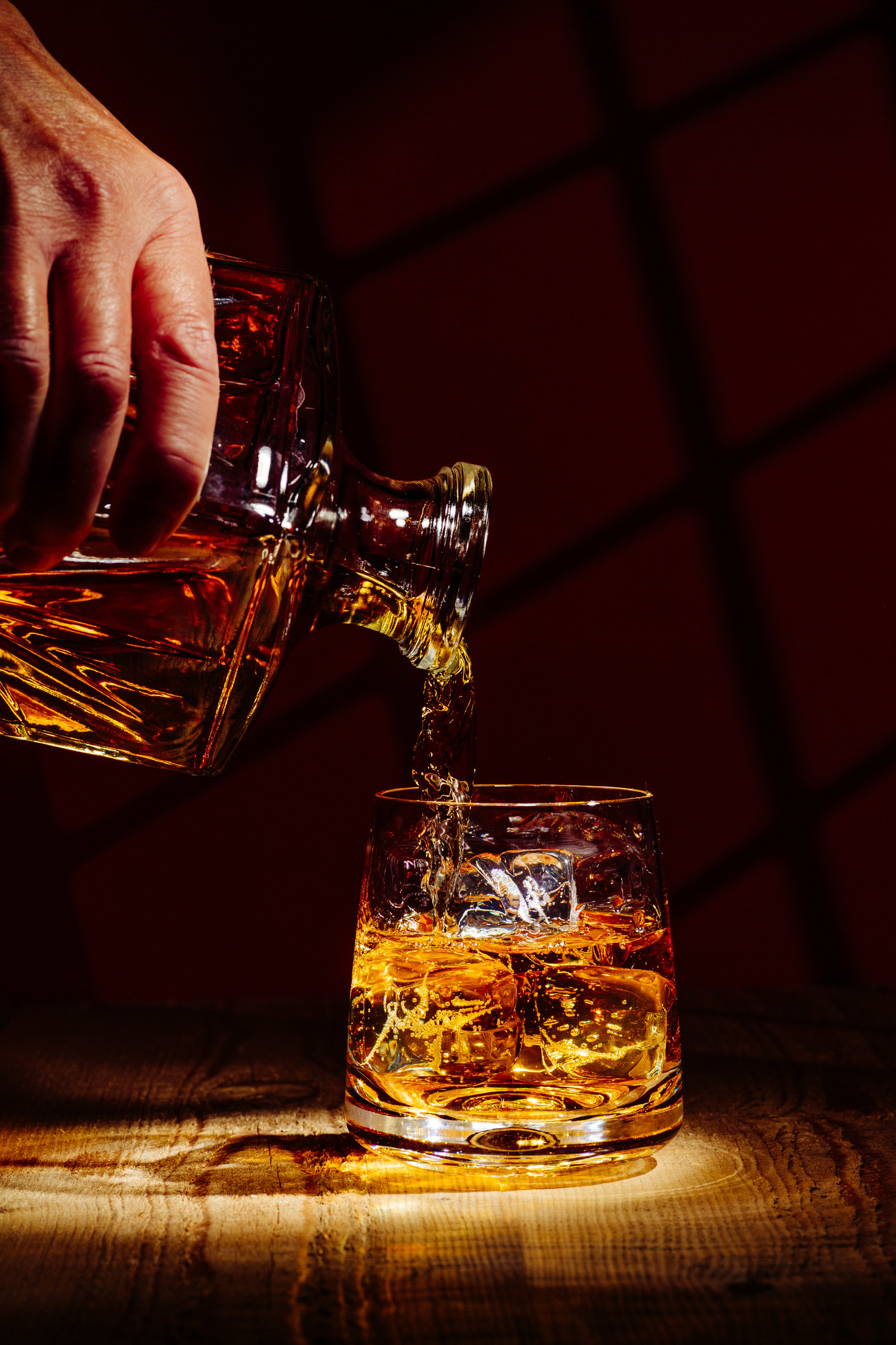 Pouring a glass of whiskey on ice.