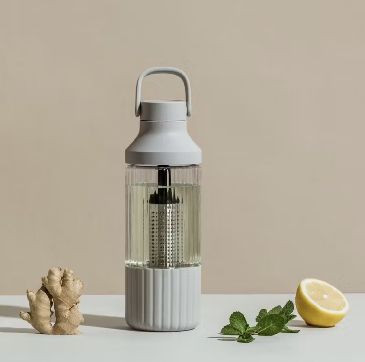 the water bottle with water and lemon, mint, and ginger nearby