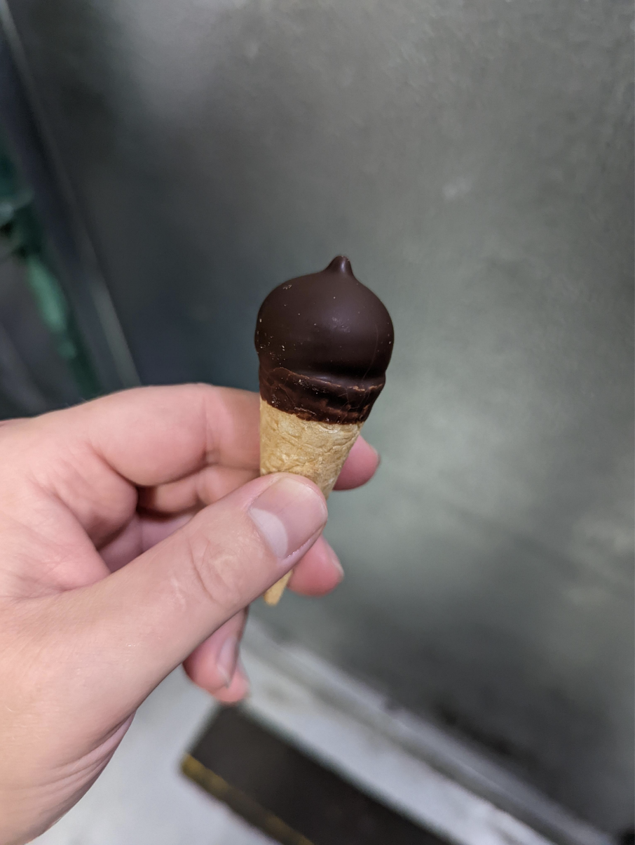 A hand holding a tiny ice cream drumstick