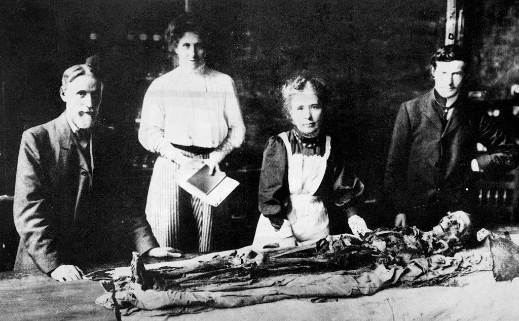 old photo of four people with a mummy