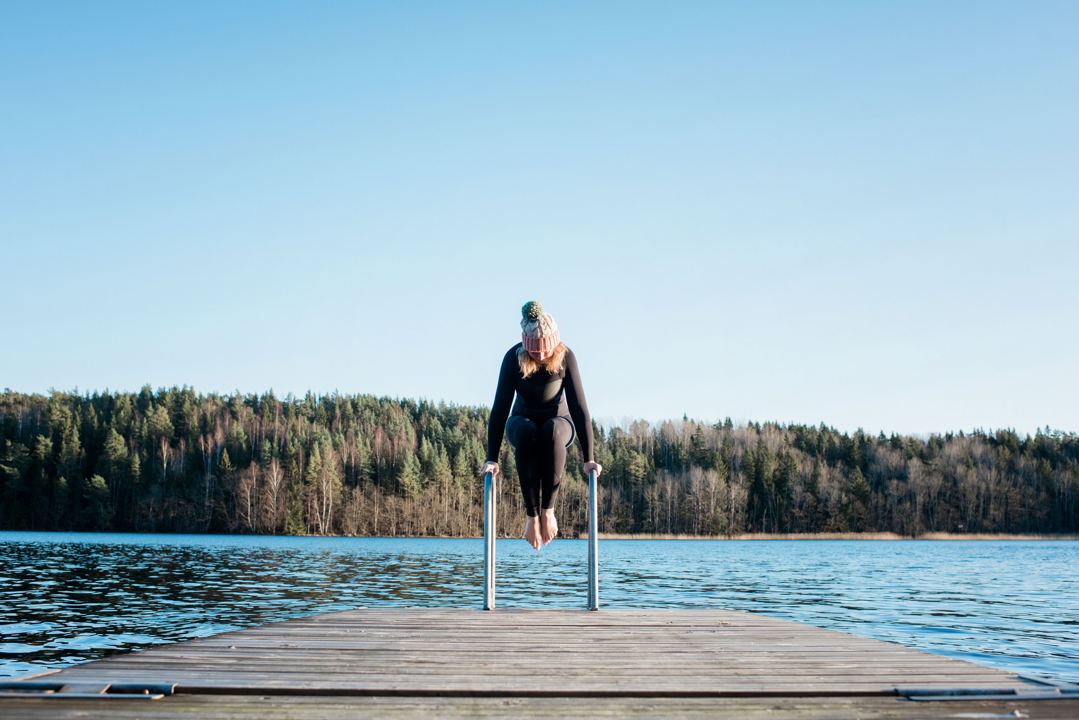 A woman getting ready to plunge into a lake from a dock
