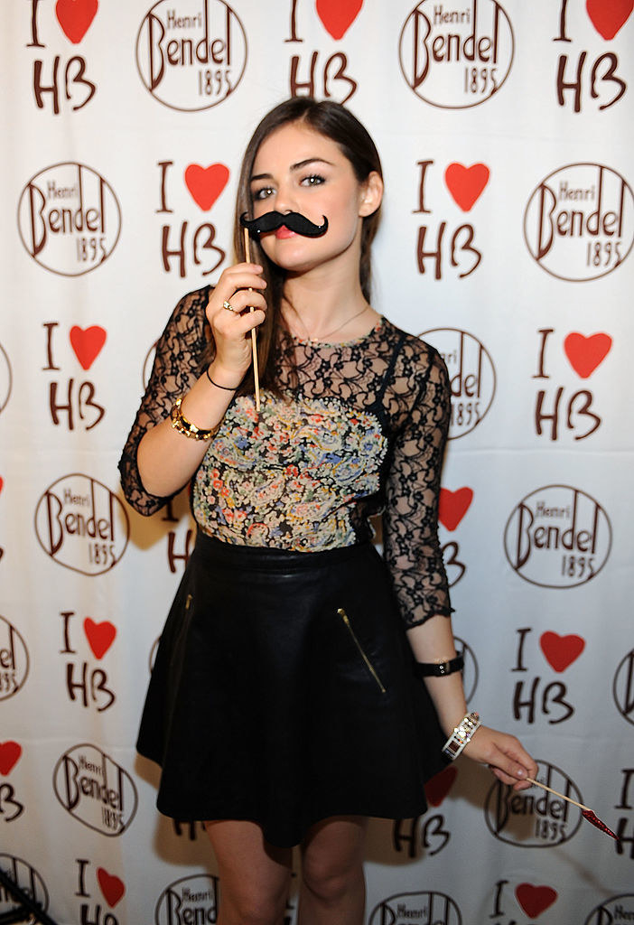 woman holding up a mustache prop to her face