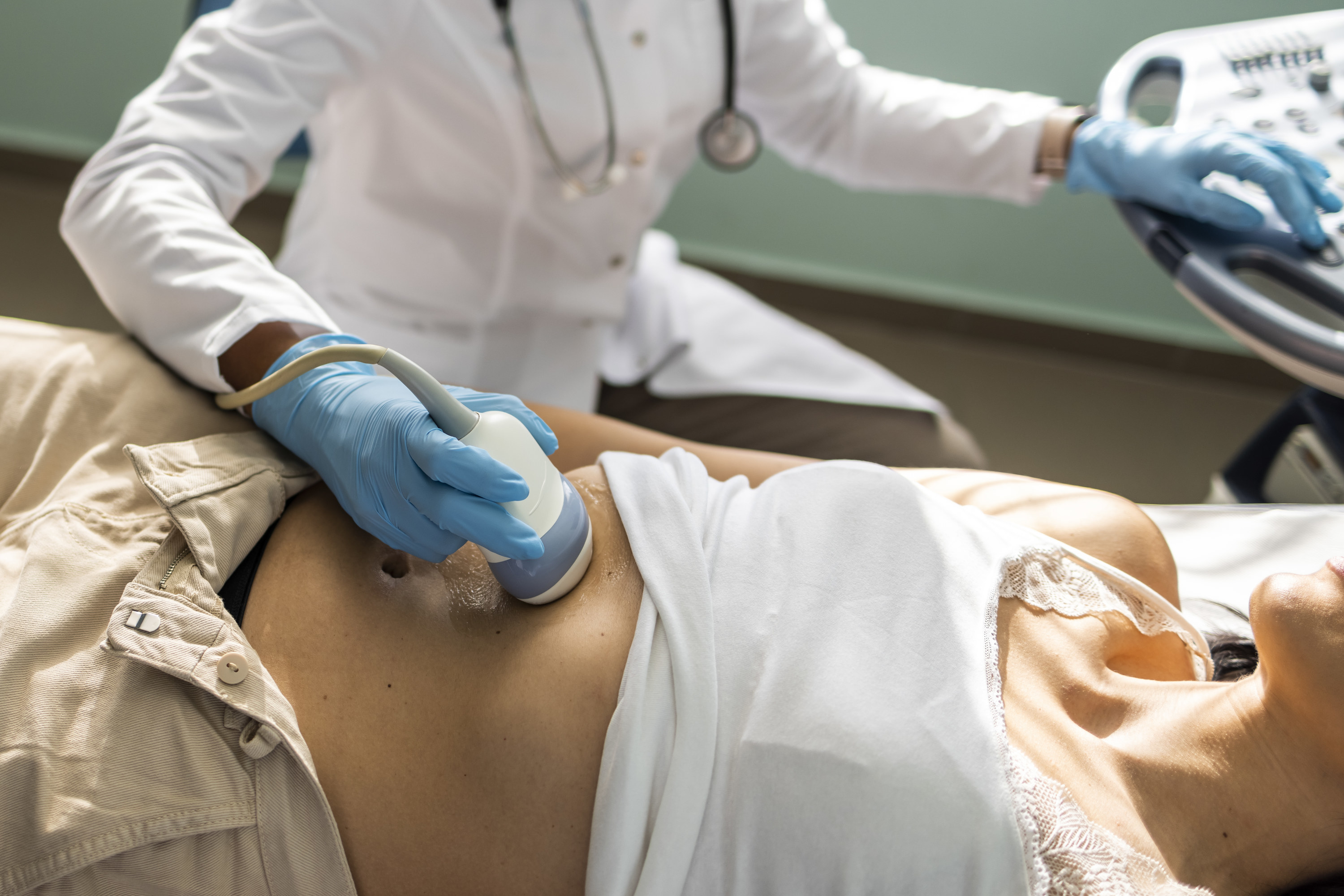 Doctor examining woman with ultrasound scanner device