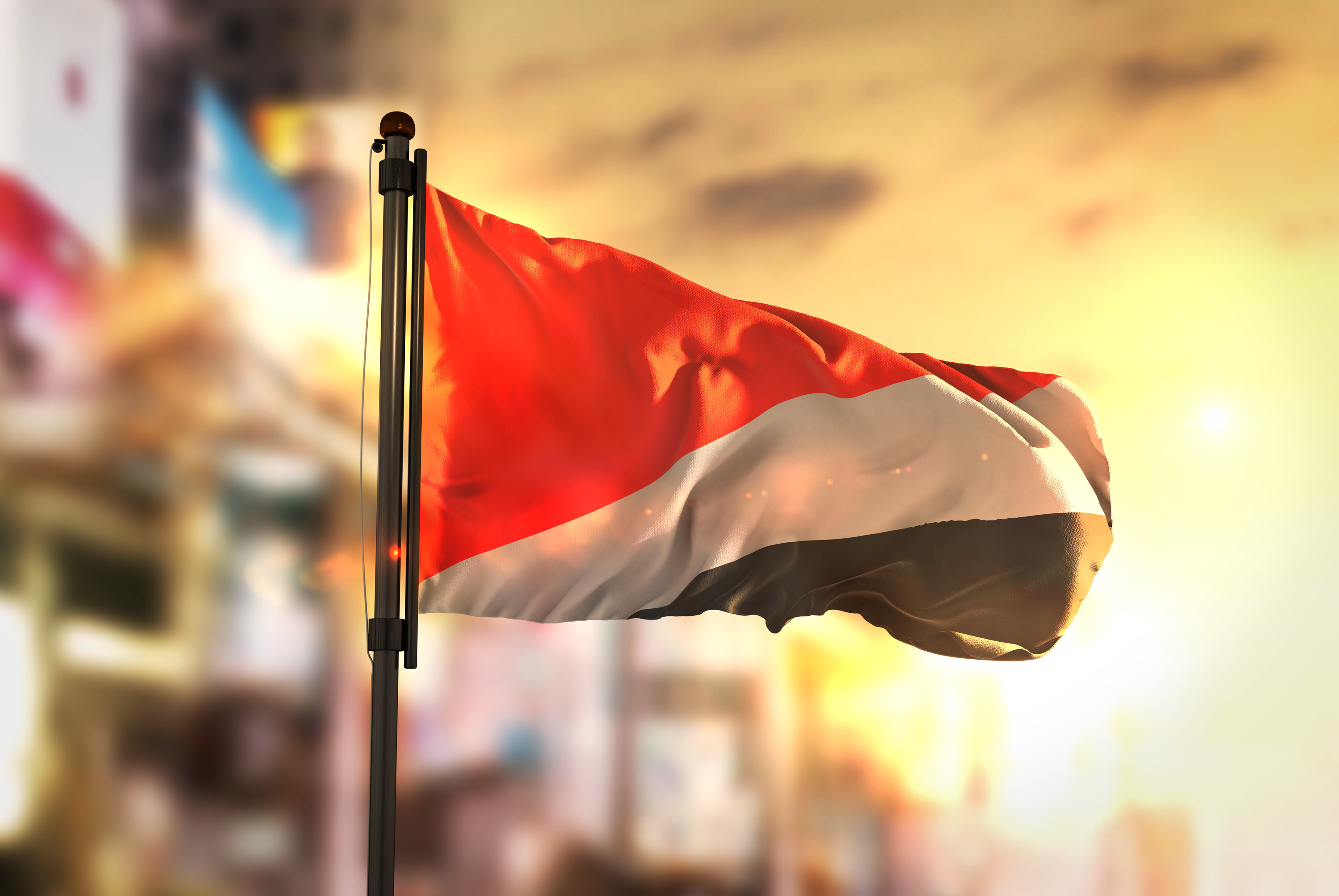 Principality of Sealand Flag Against City Blurred Background At Sunrise Backlight