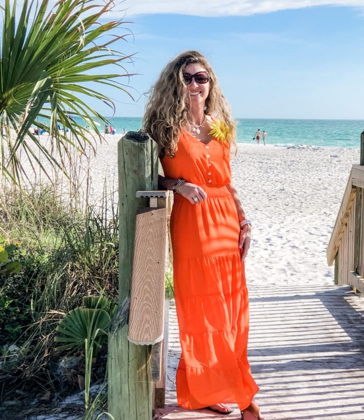 a reviewer wearing the orange dress at the beach