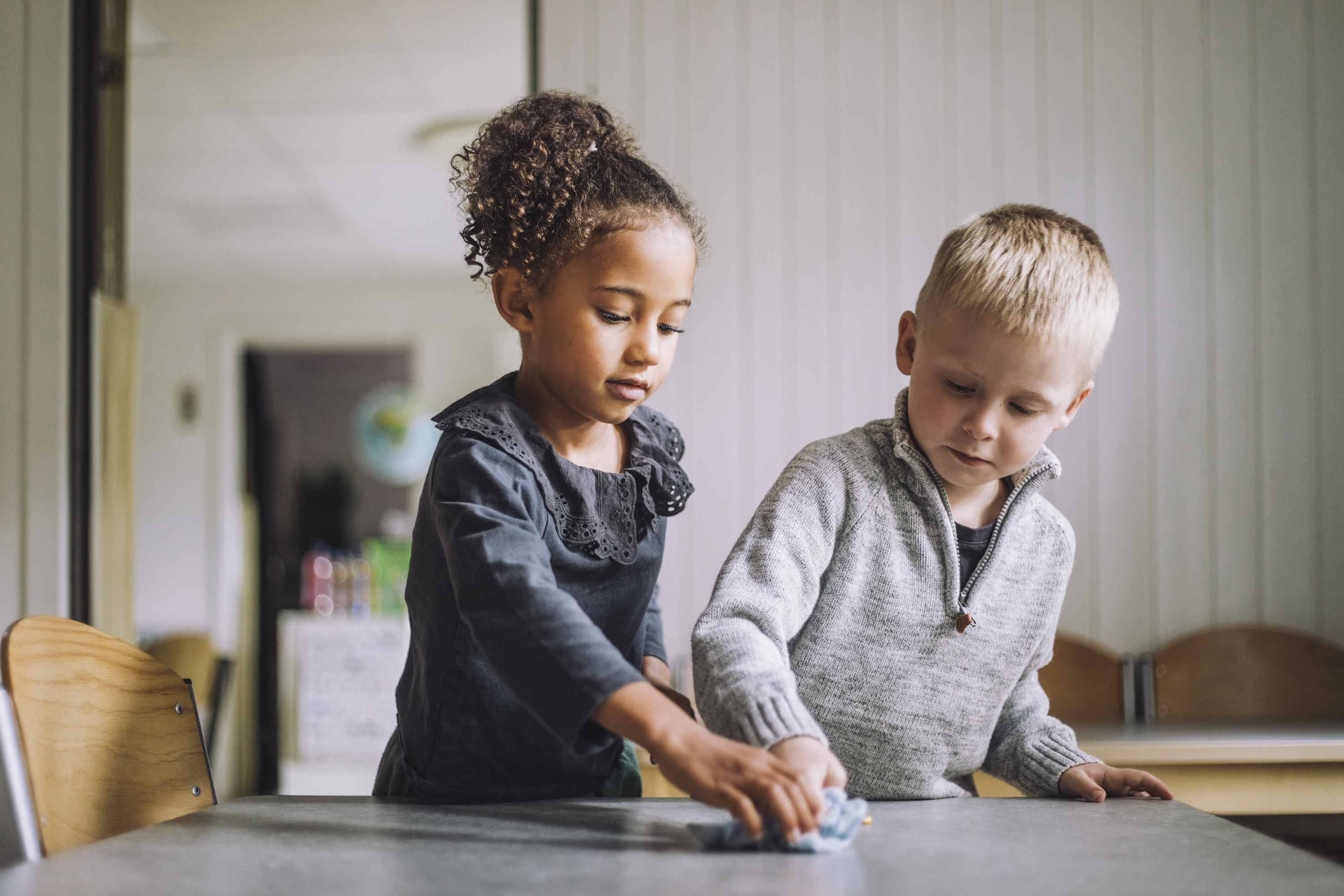 A little girl and boy cleaning a table