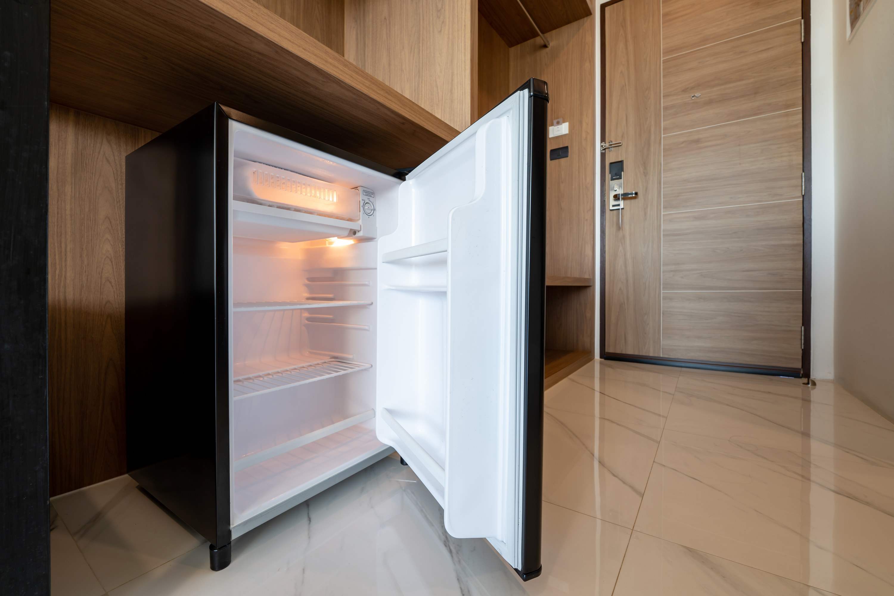 A hotel mini fridge that&#x27;s empty with the door open