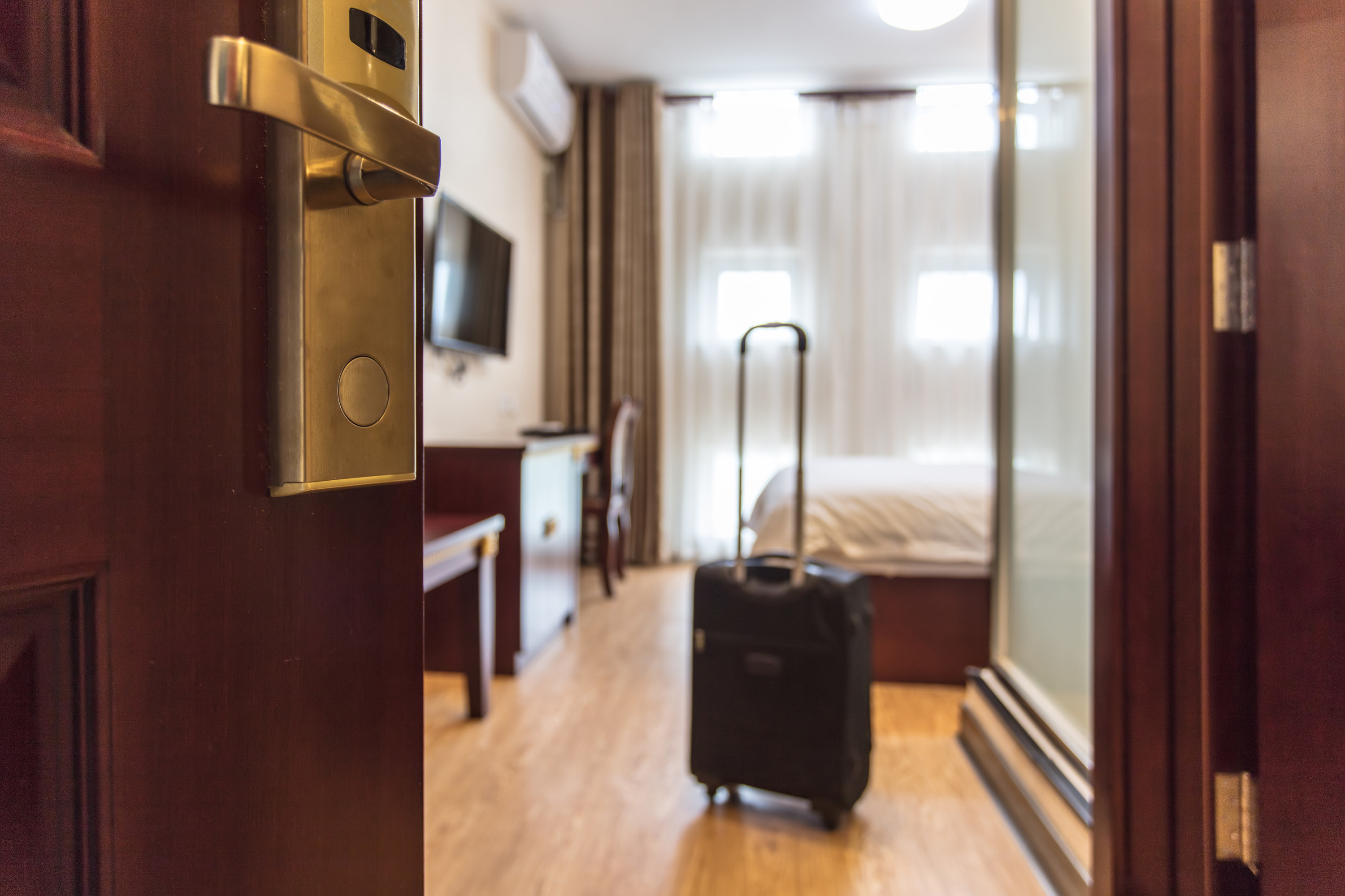 A black suitcase in a hotel room with an open door