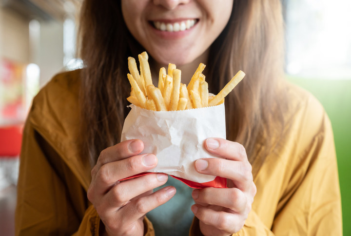 A woman holding French fries and smiling