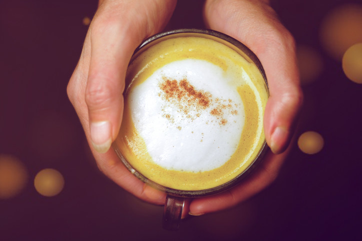 A hand cupping a pumpkin spice latte