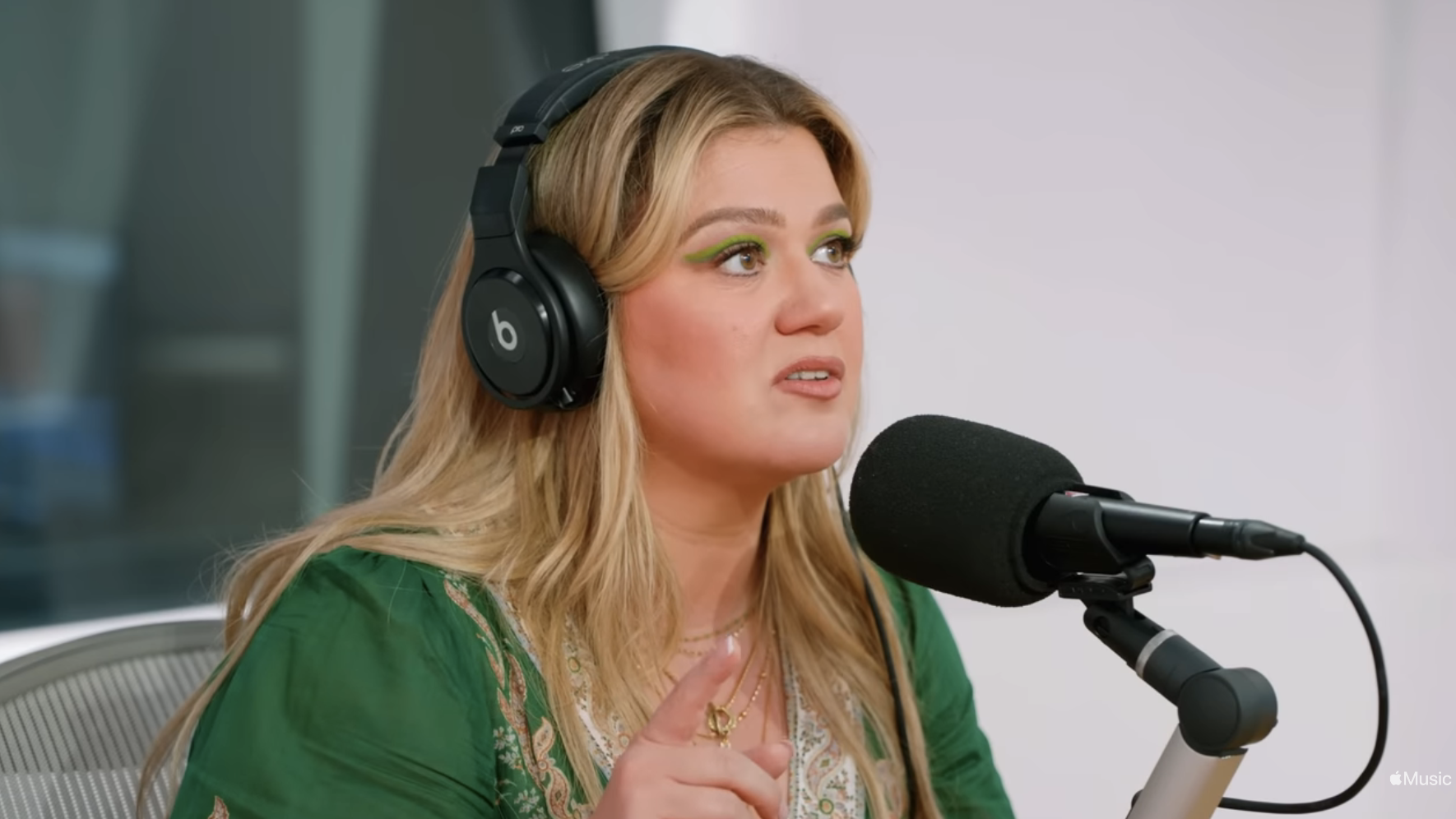 Close-up of Kelly seated at a microphone