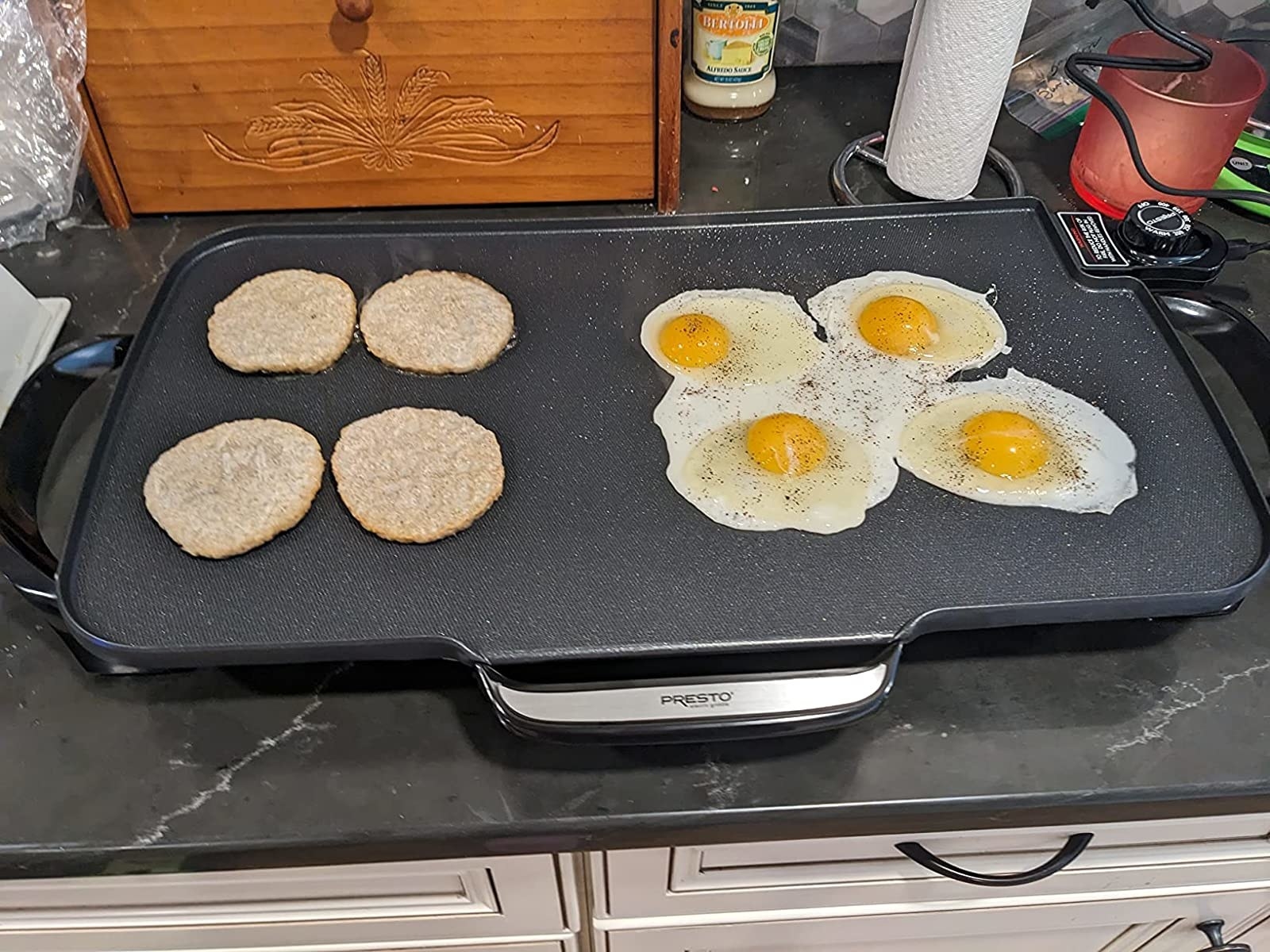 Reviewer cooking up sausage patties and fried eggs on griddle