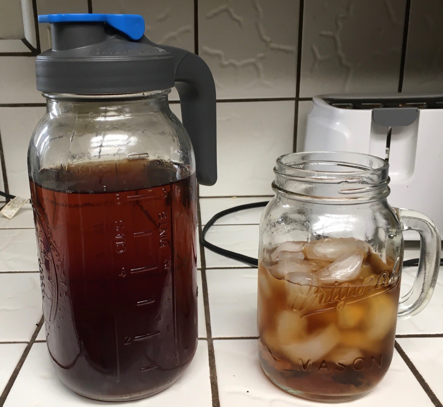 Reviewer&#x27;s pitcher filled with tea next to mason jar glass filled with iced tea