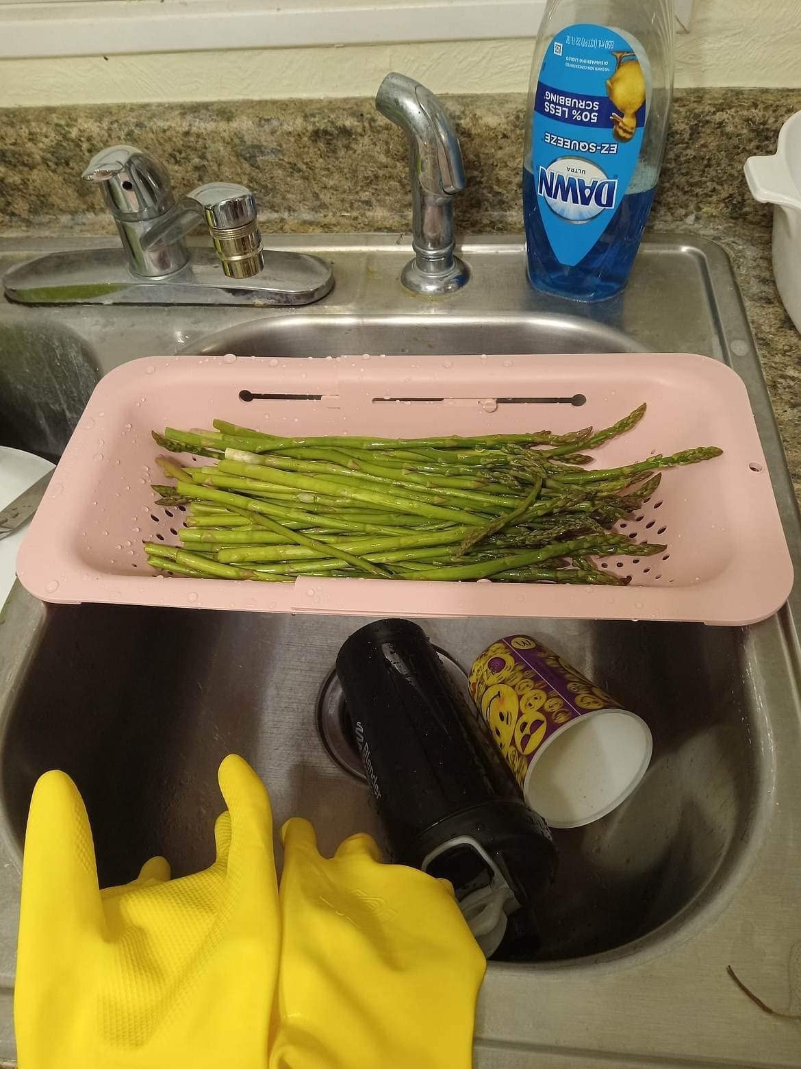 Reviewer&#x27;s strainer over sink with asparagus resting inside to be rinsed