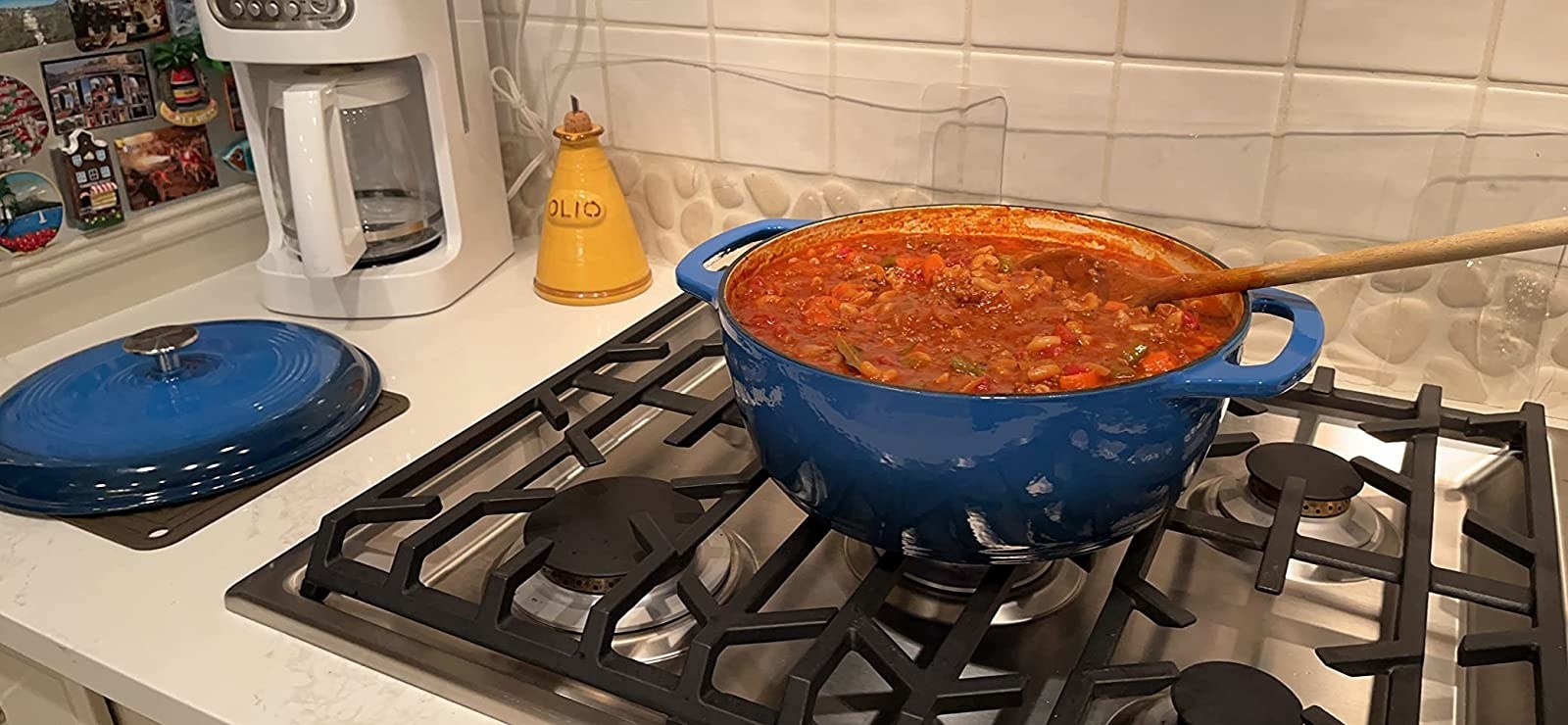 Reviewer cooking vegetable stew on stove in blue dutch oven