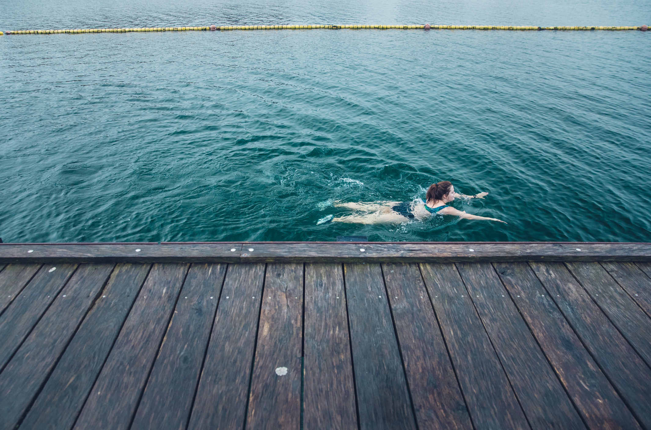 A woman swimming next to a dock.