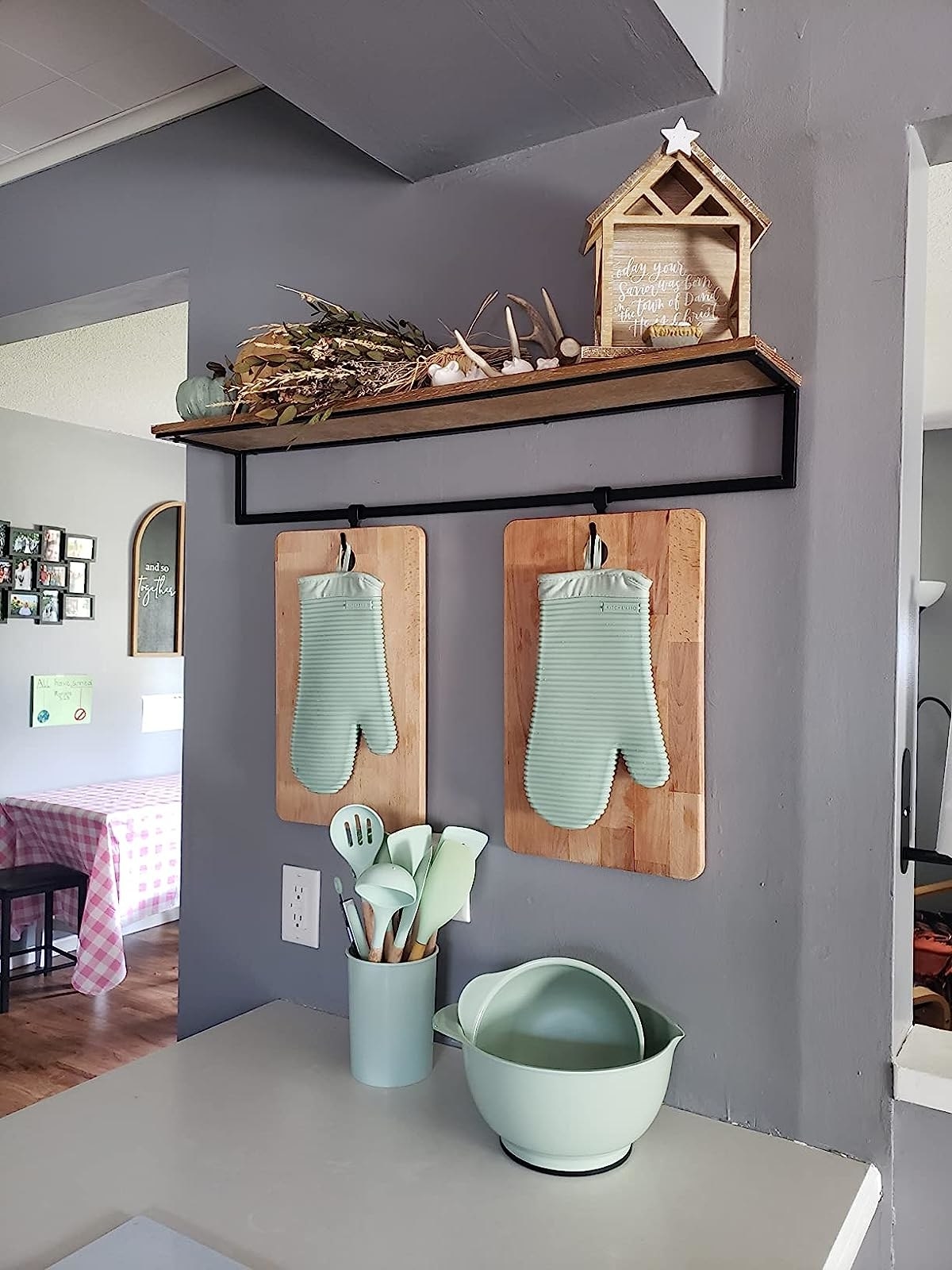 The teal mitts hanging in front of cutting boards on kitchen wall