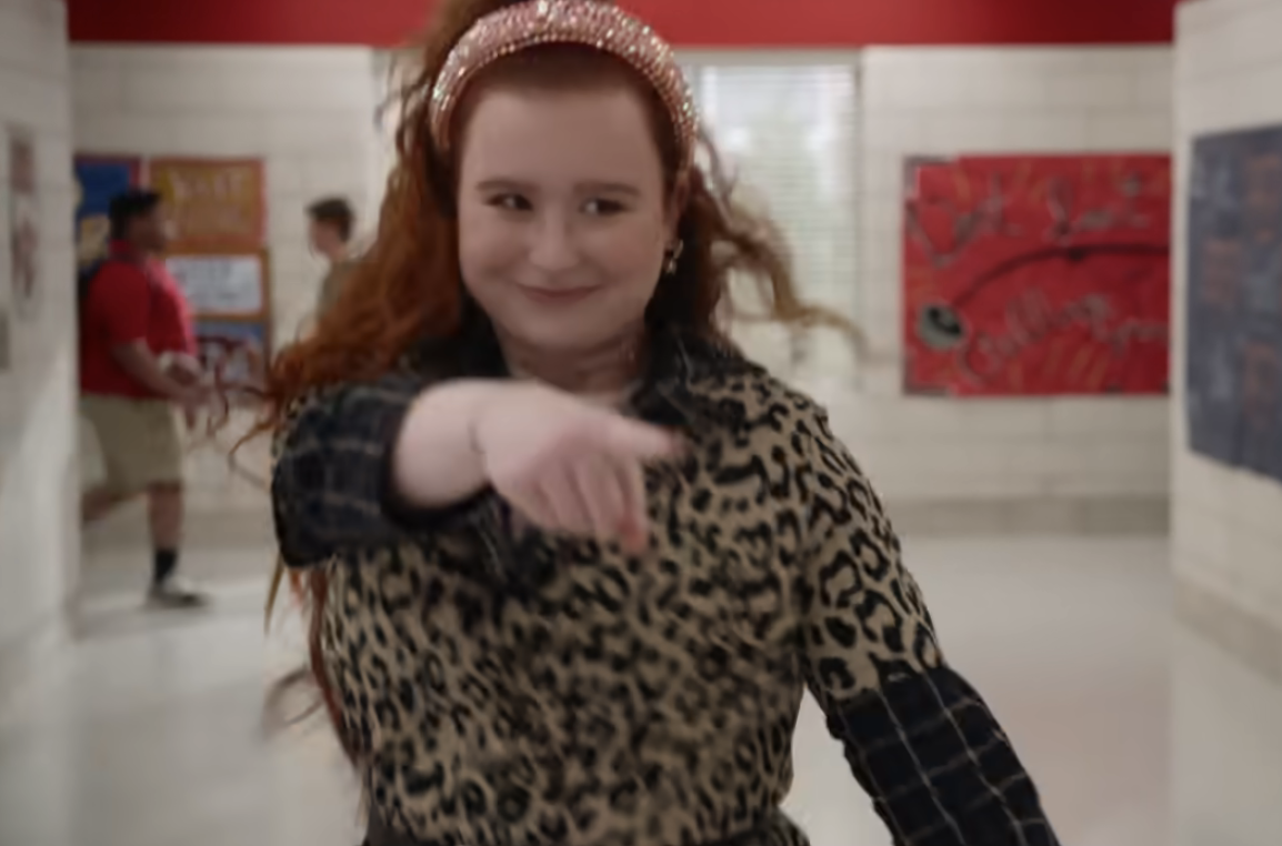 Julia Lester as Ashlyn pointing and wearing a headband