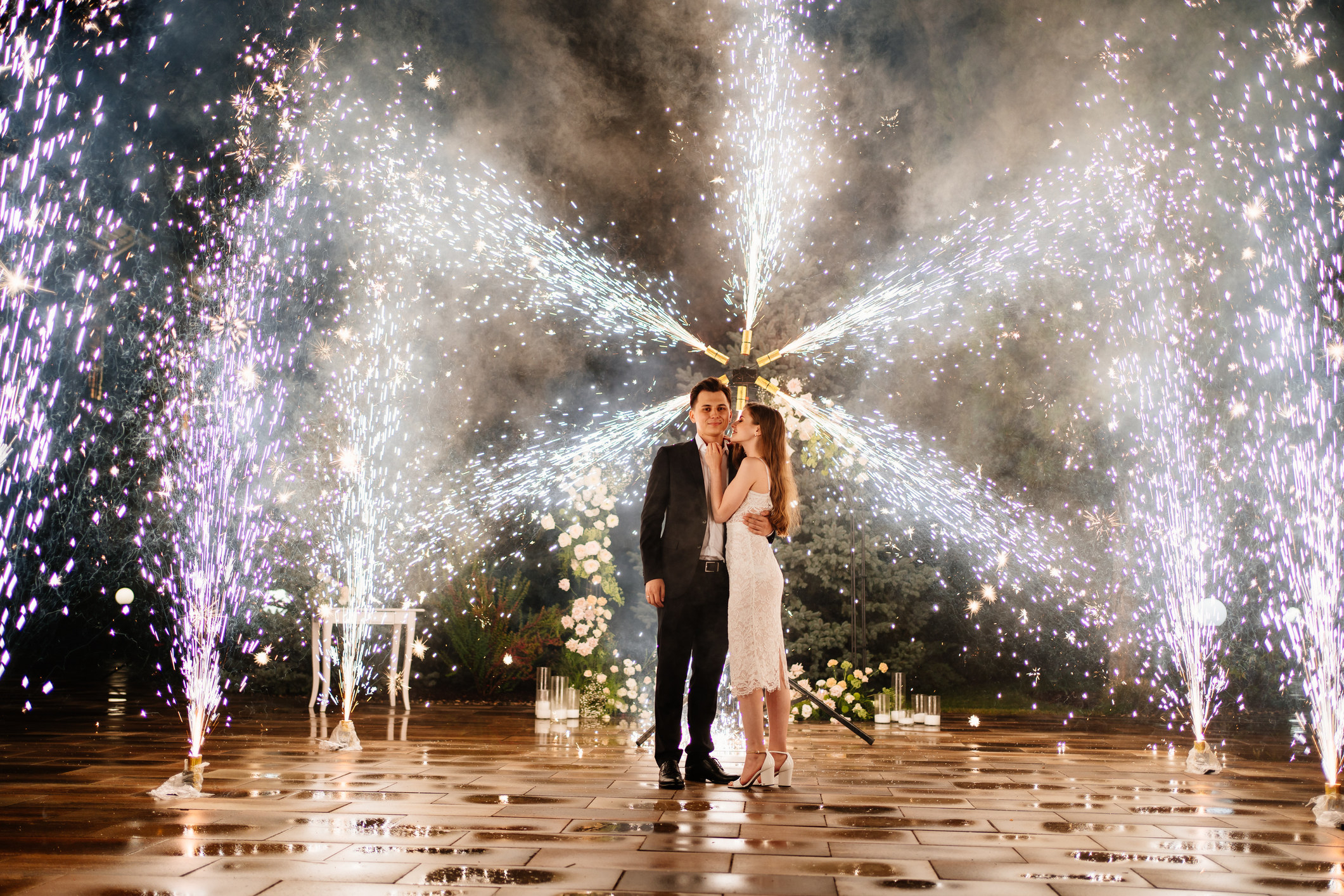 A bride and groom with fireworks behind them