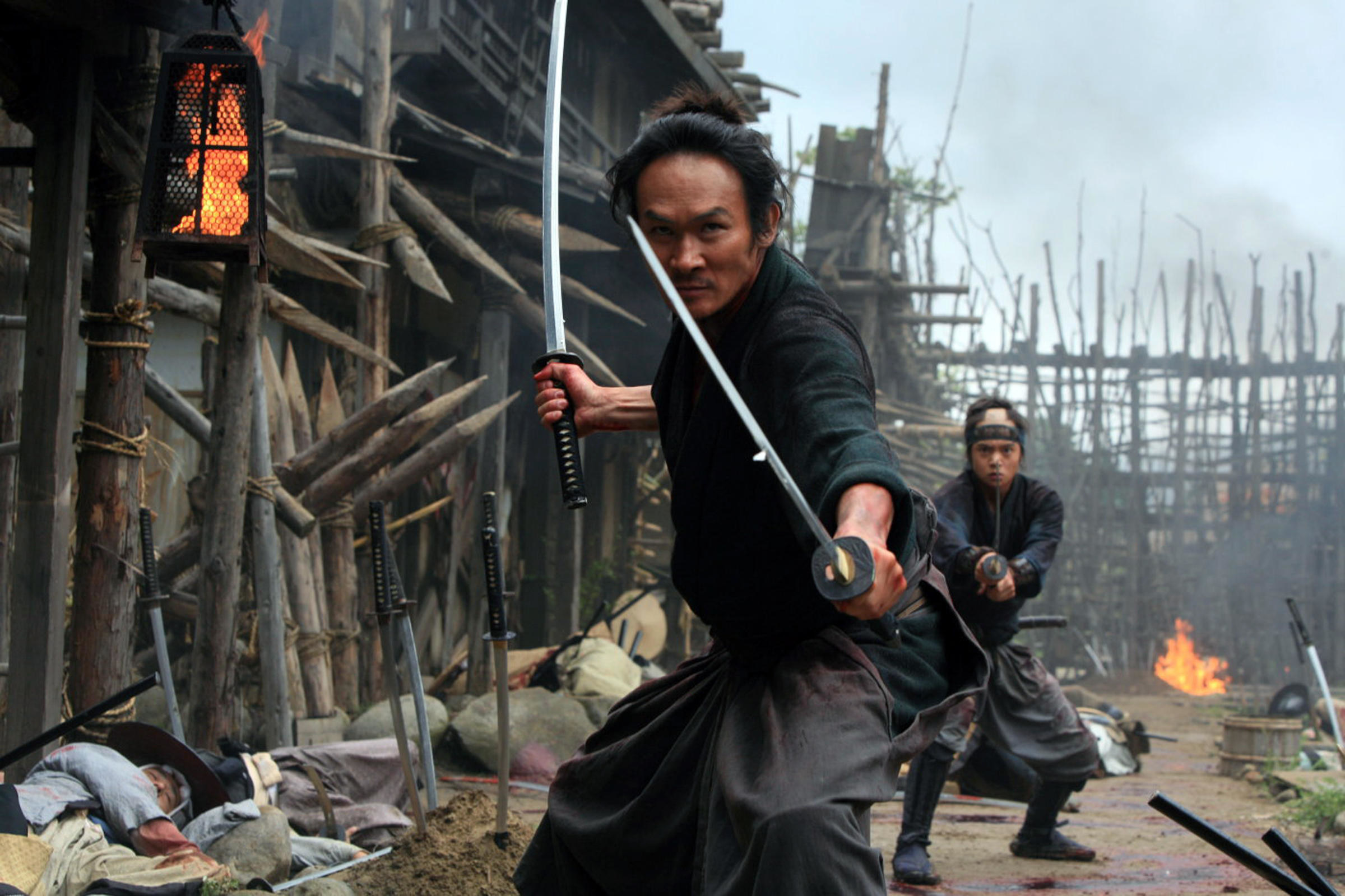A pair of ronin don their blades at their enemies in a burning village