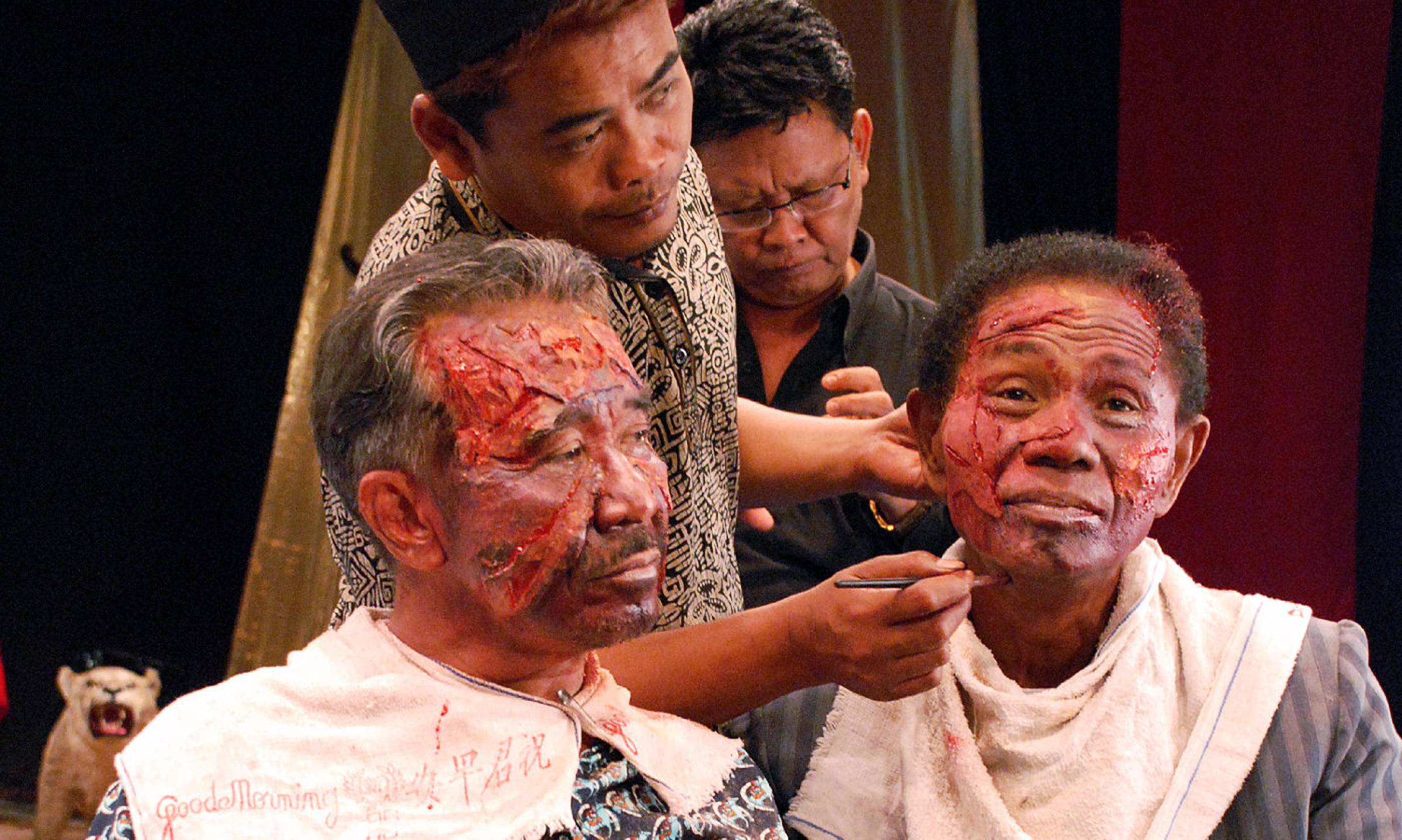 Two Indonesian men undergo special effects make-up on their face