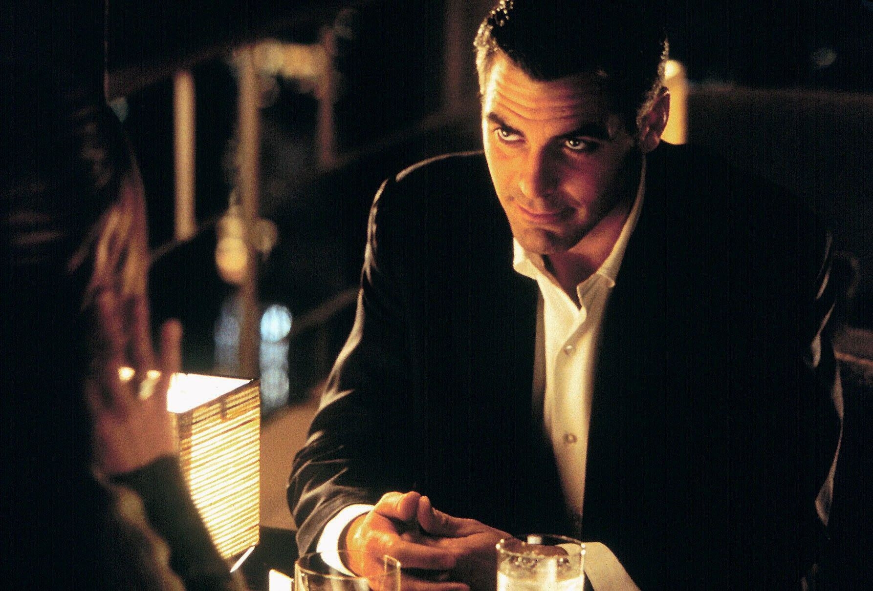 George Clooney stares seductively in a dark upscale restaurant