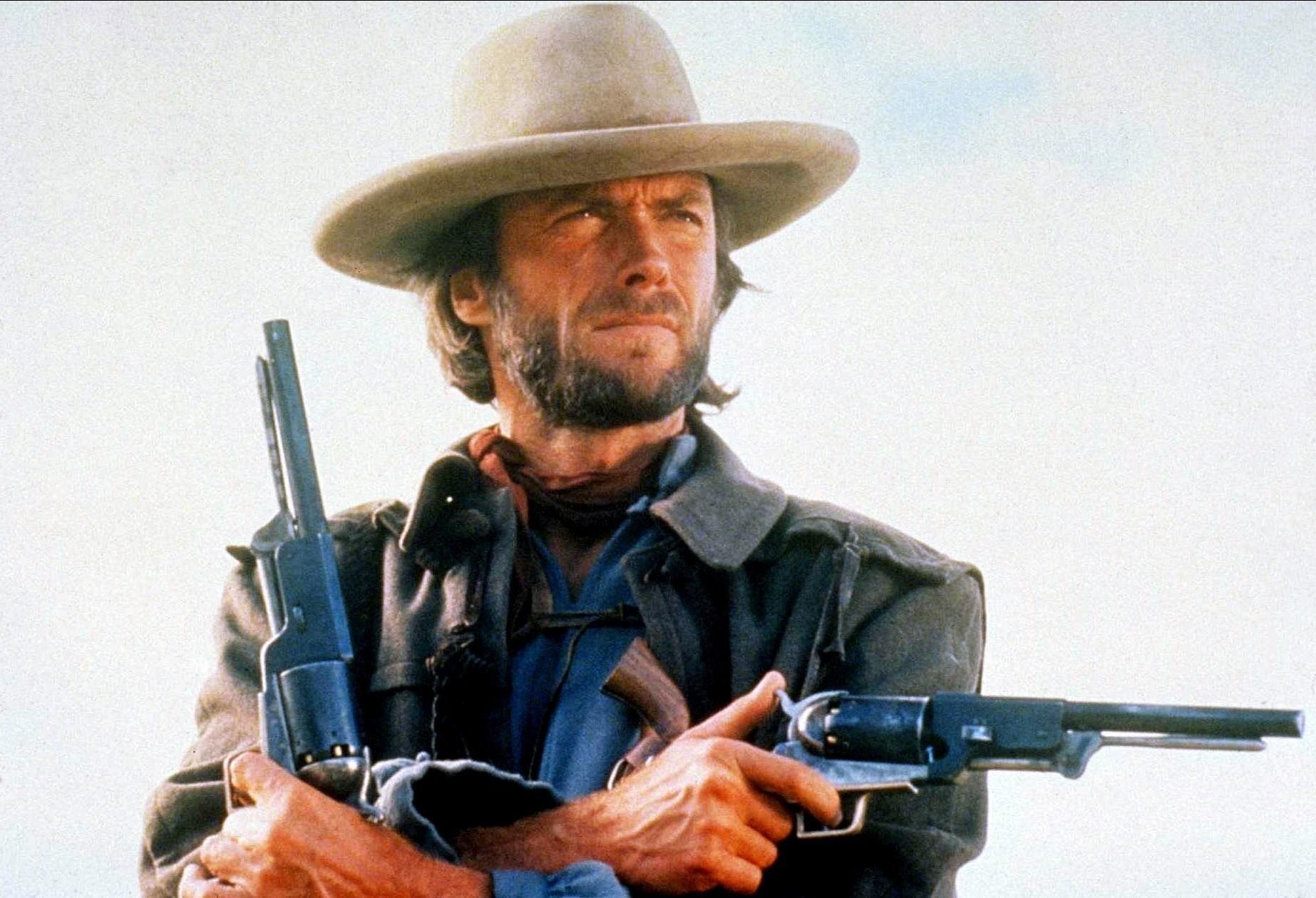 Clint Eastwood holds dual pistols in a classic cowboy get-up