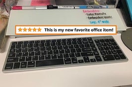 Reviewer pic of the long rectangle-shaped whiteboard with groove across the top with markers in it in with a keyboard in front of it and text that reads "this is my new favorite office item"