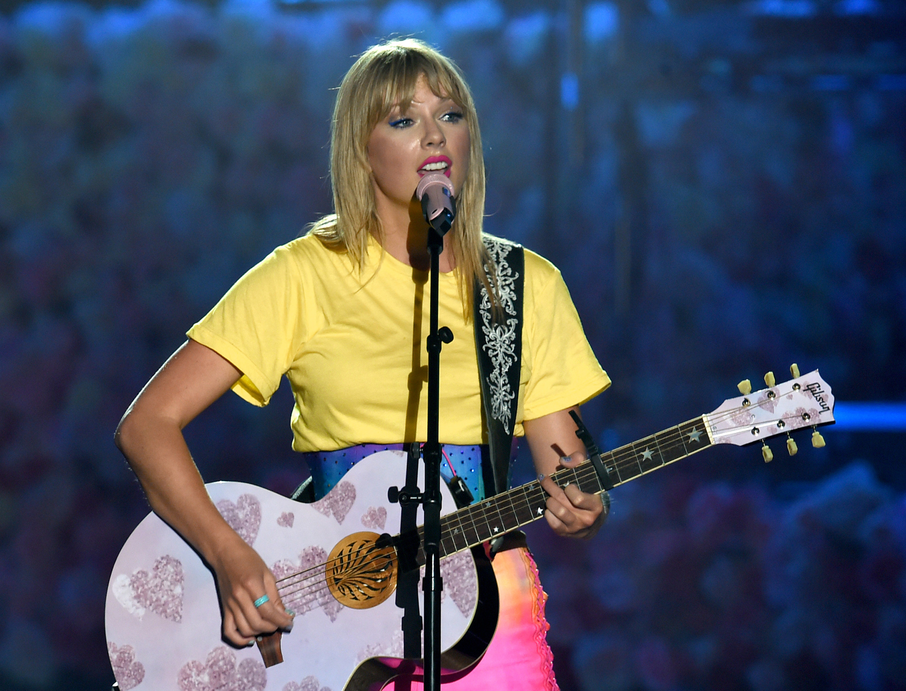 Close-up of Taylor playing a guitar and singing onstage