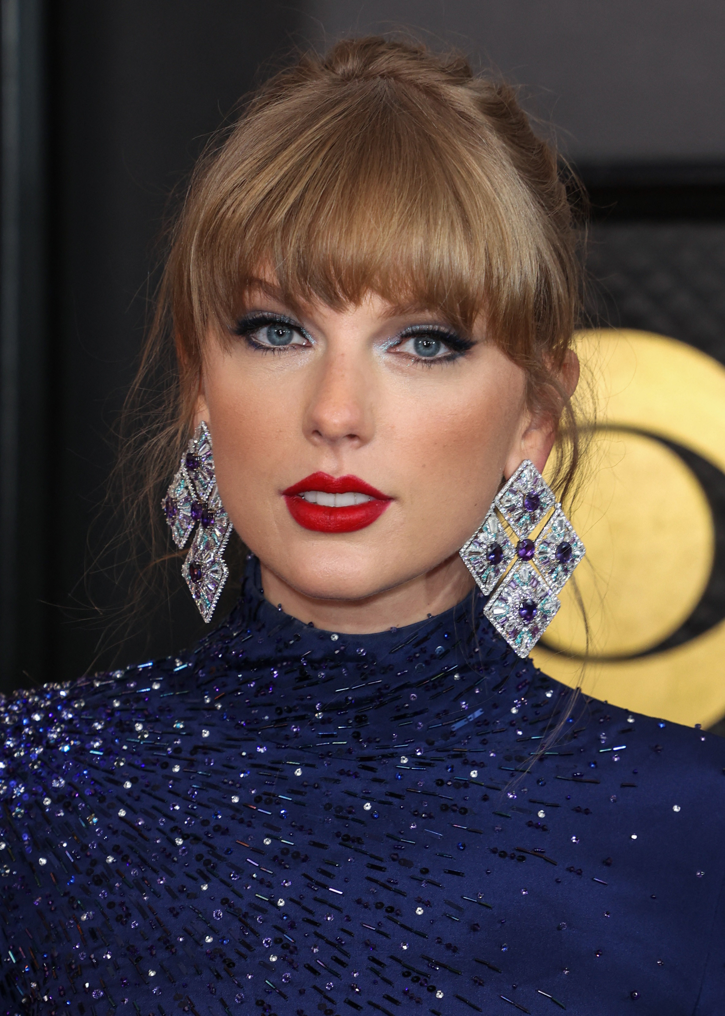 Close-up of Taylor in long, sparkly earrings and a sparkly outfit