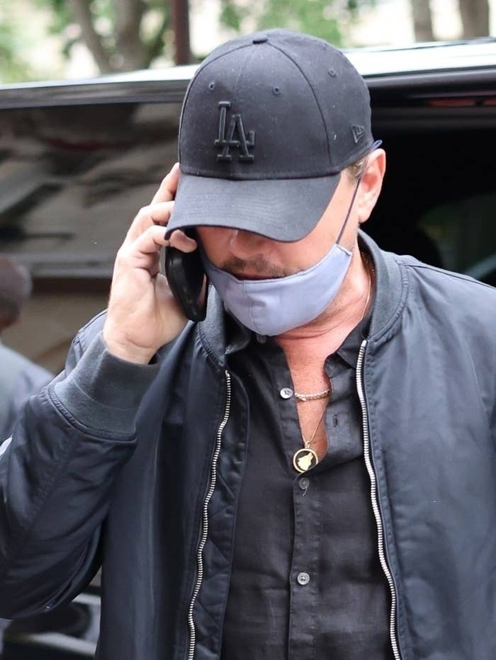 Close-up of Leo on the phone and wearing a cap and wolf necklace