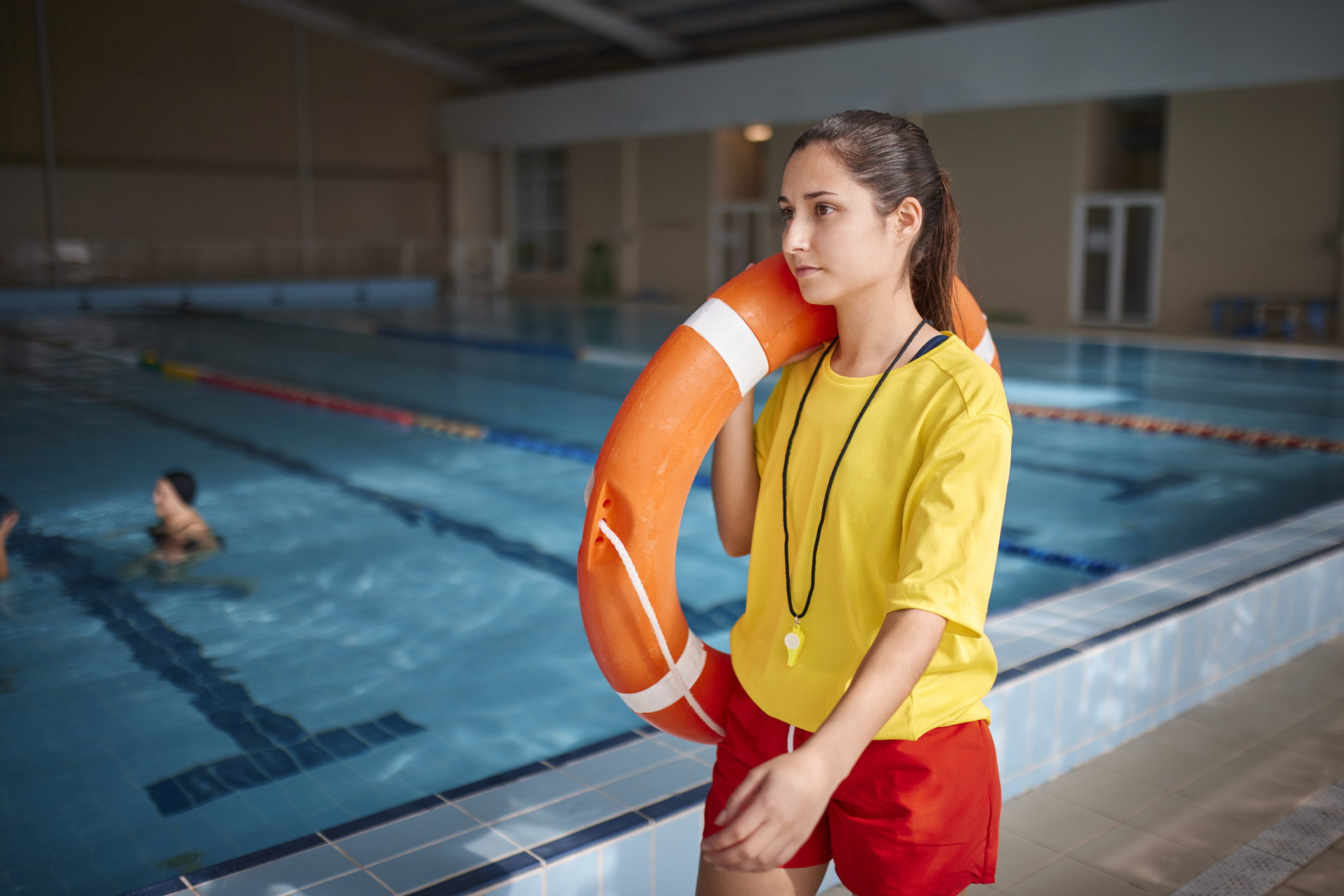 Lifeguard walking around indoor pool