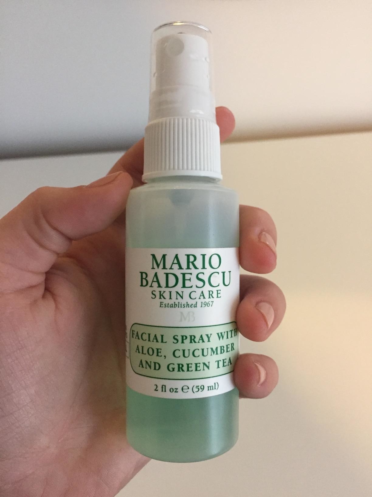 a reviewer holding the travel size spray