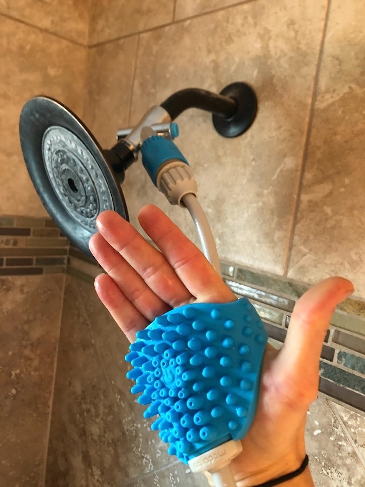 reviewer holding blue shower head attachment