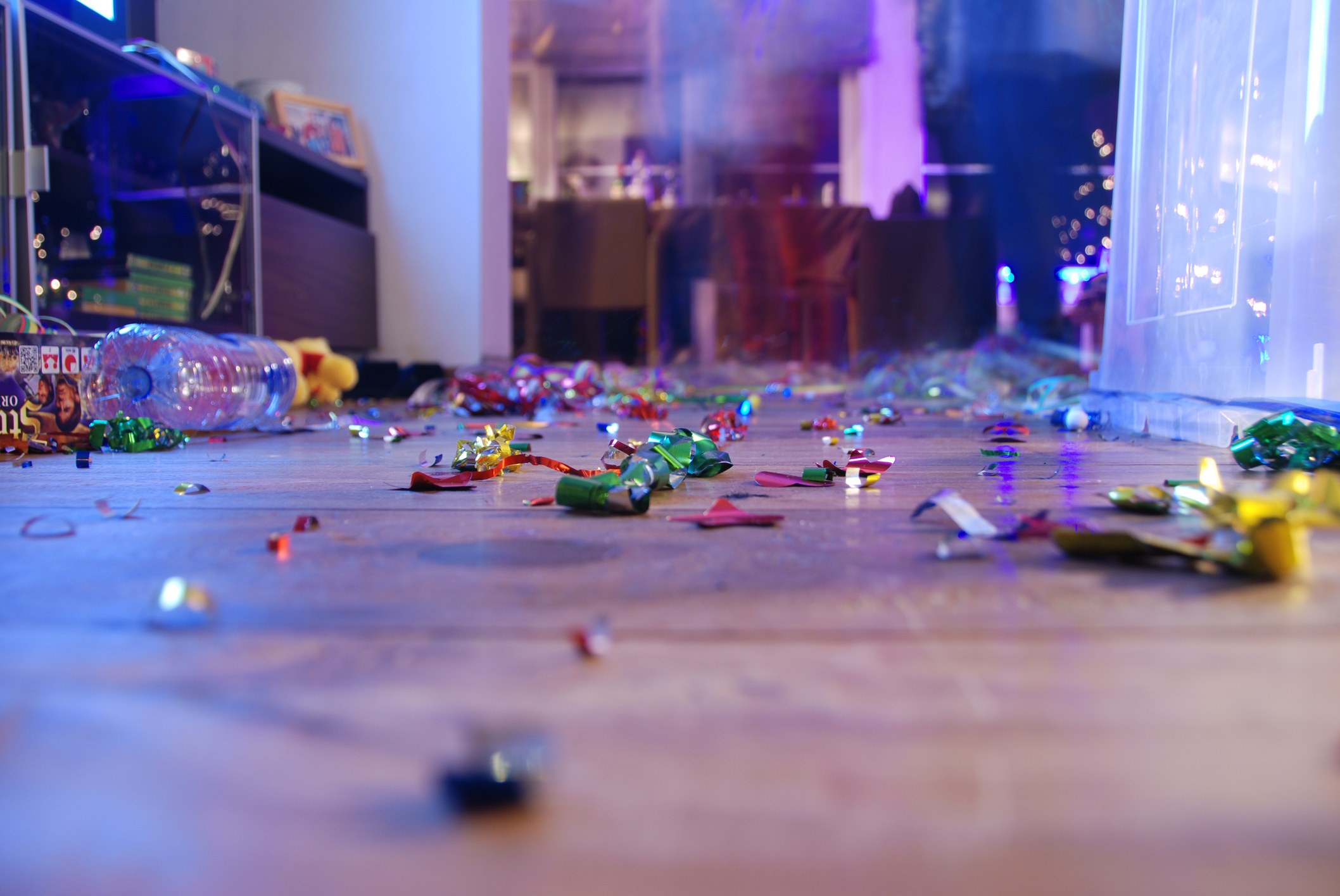 the aftermath of a party, featuring empty bottles and confetti all over the floor