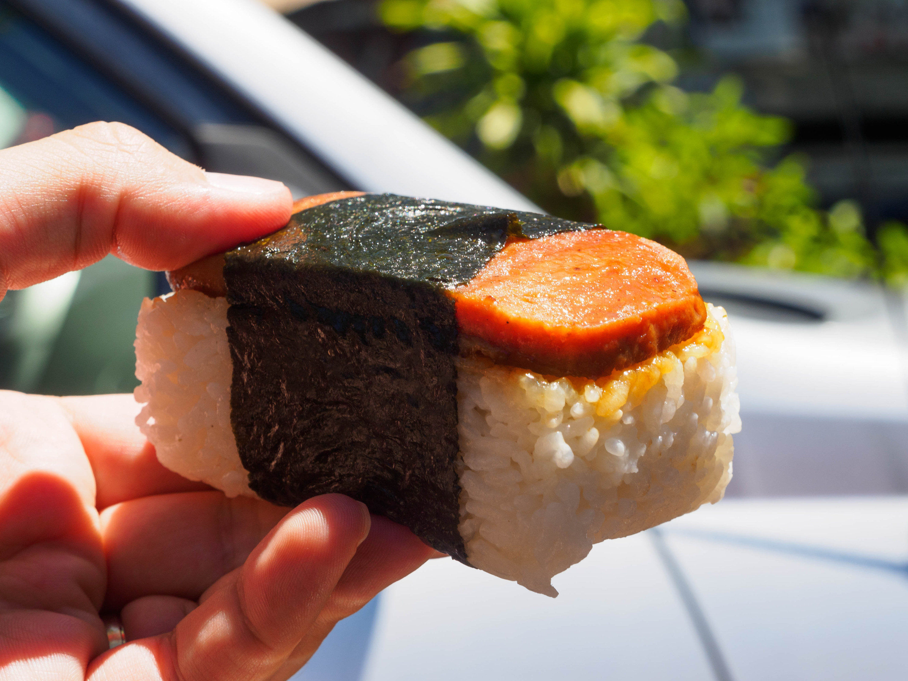 A hand holding spam musubi