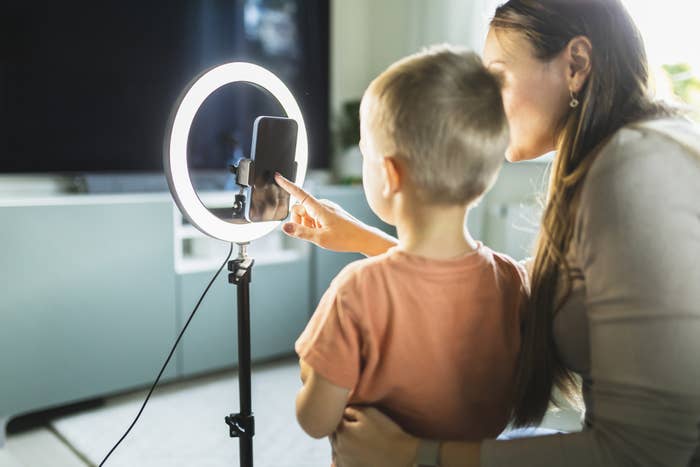 A mother with her son taking a selfie in front of a ring light